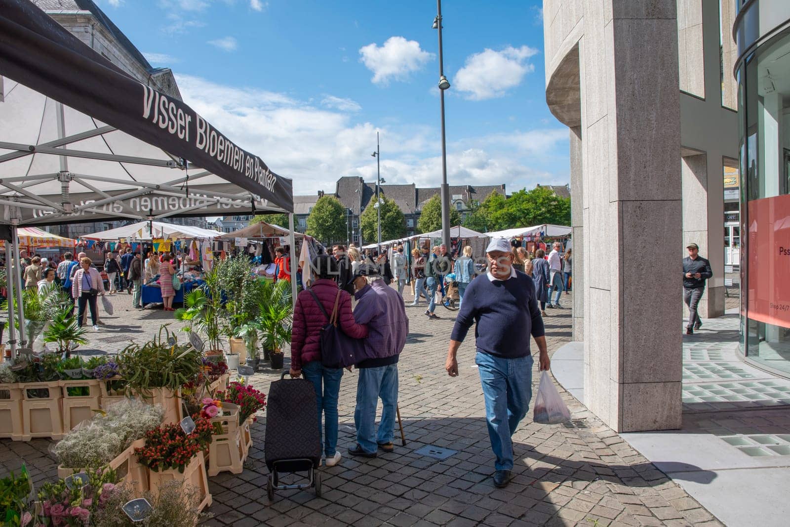 People walk among Variety of flower choices at the market in the central square in Maastricht, Netherlands, August 27, 2021. High quality photo