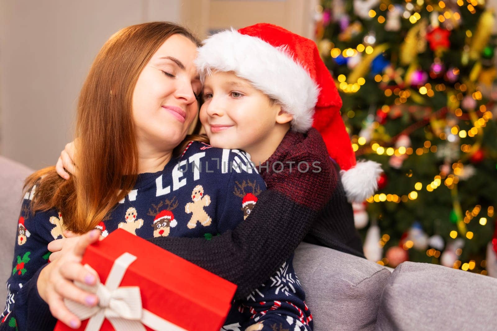 Mother and son hugging and giving gifts at christmas at home in the living room.