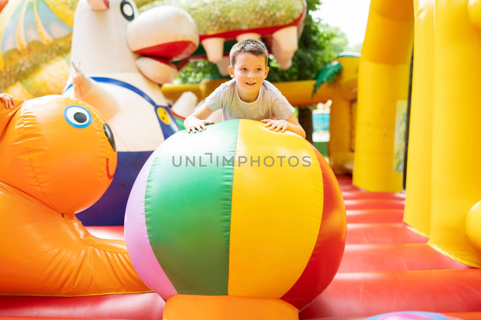 Happy boy having a lots of fun on a colorful inflate castle. Colorful playground. Activity and play center for kids.