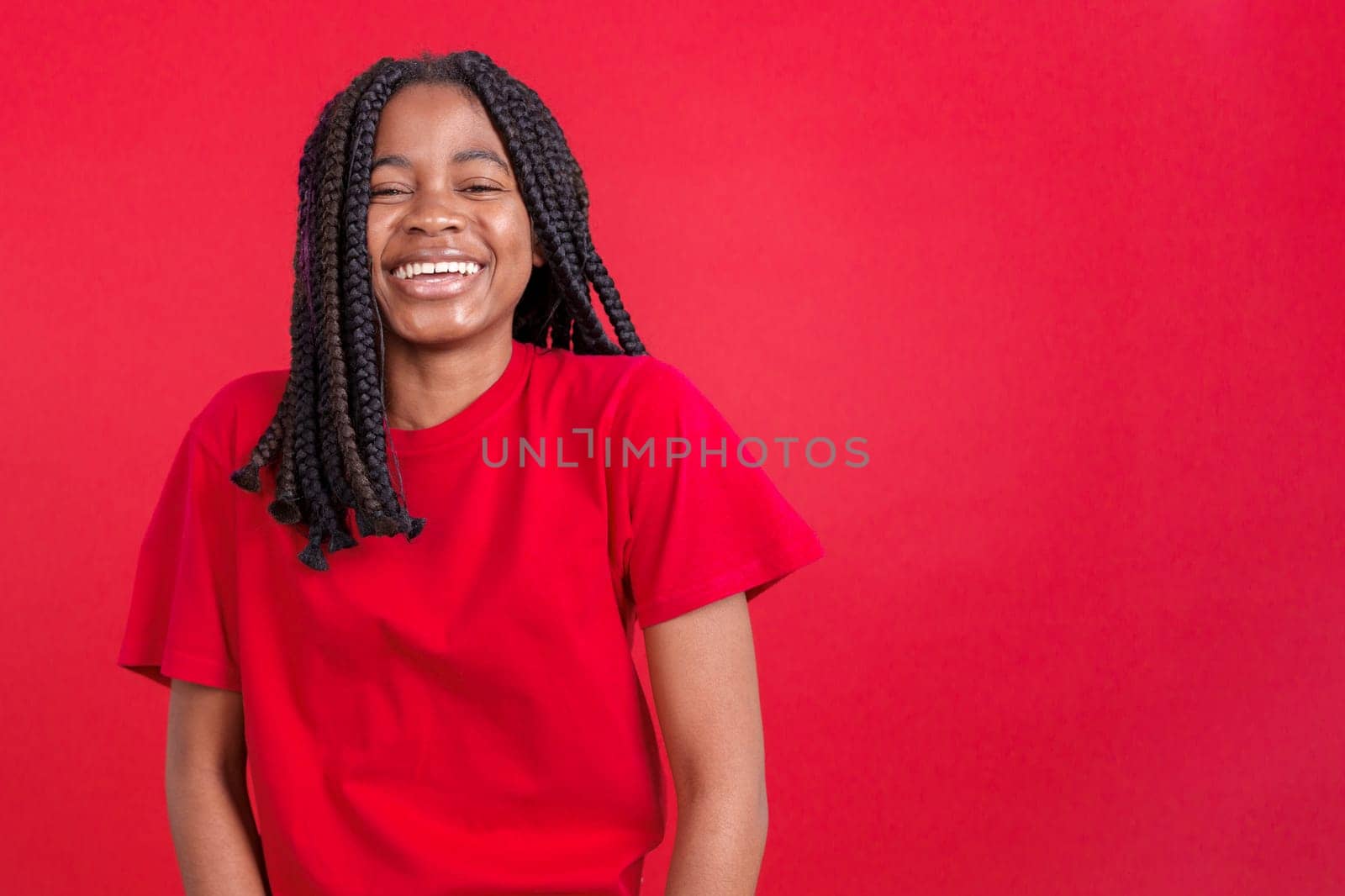 Happy african woman smiling at the camera in studio with red background