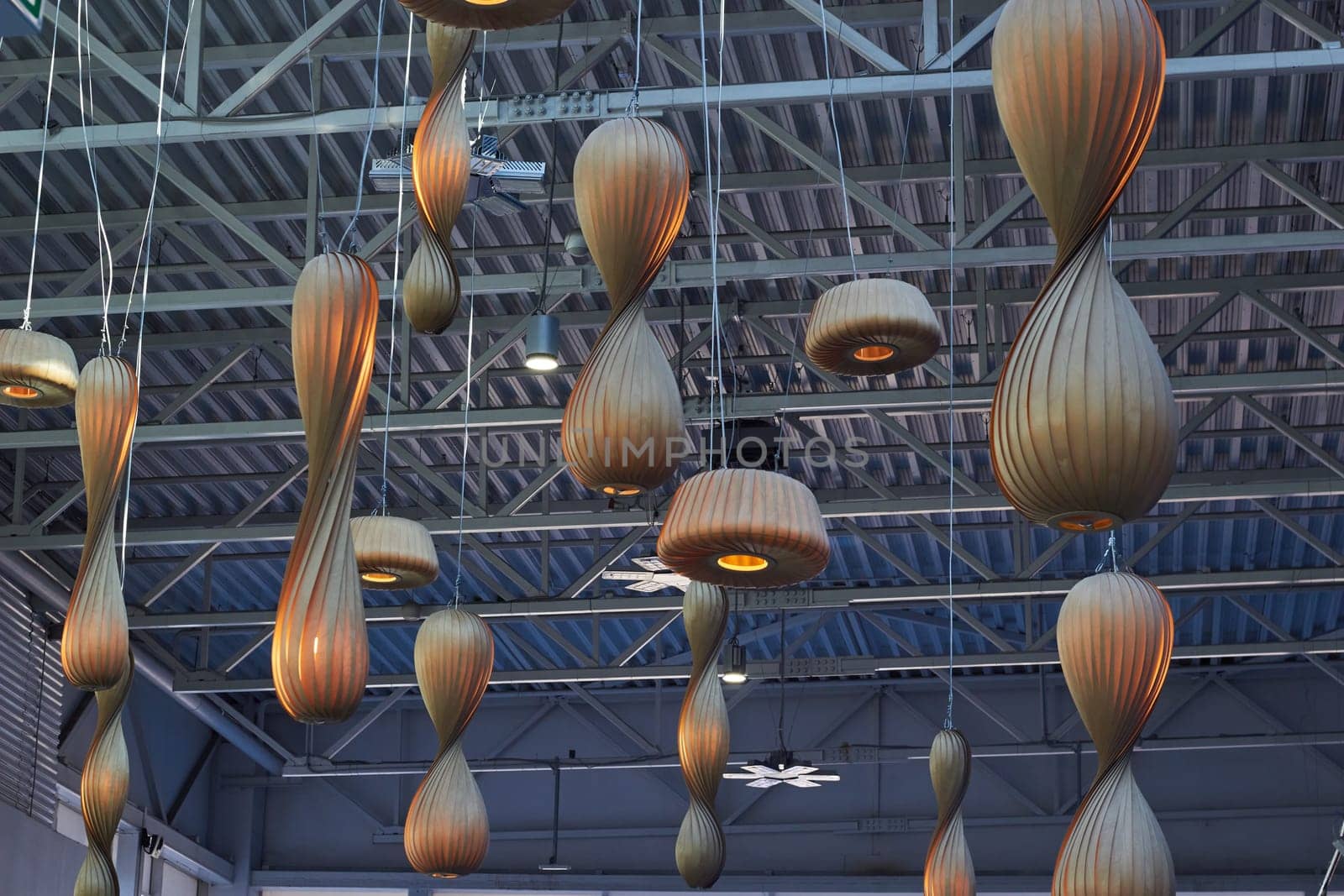 Large wooden lamps hanging from the ceiling. Metal Ceiling of the shopping center. Lighting of shops.