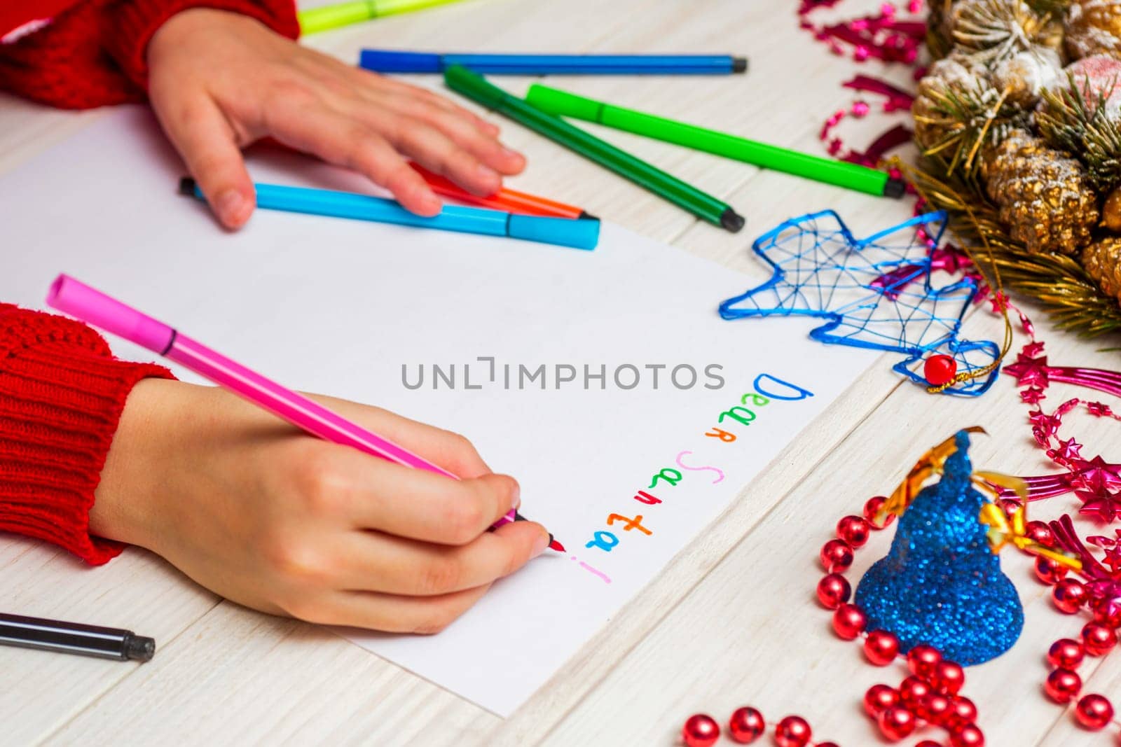 Little child writes letter to Santa. Kids hand with felt-tip pen writes a letter to Santa. Wishlist