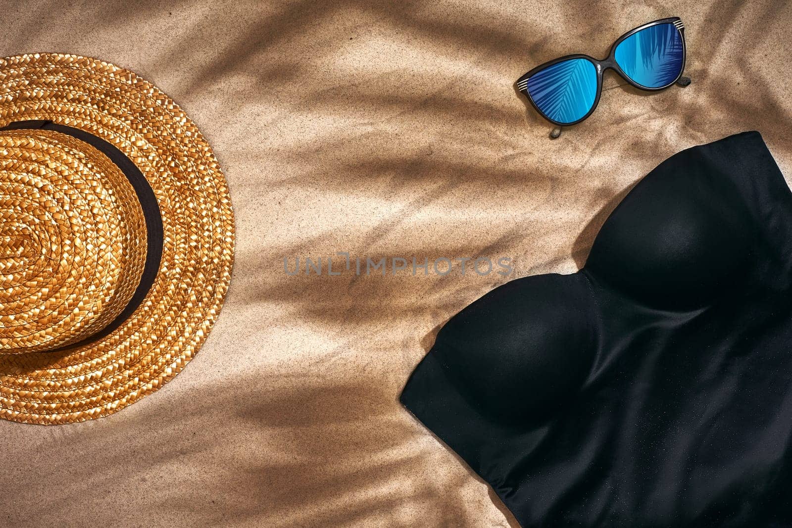 Women's beach accessories or summer outfit on sand background. Top view with copy space by nazarovsergey