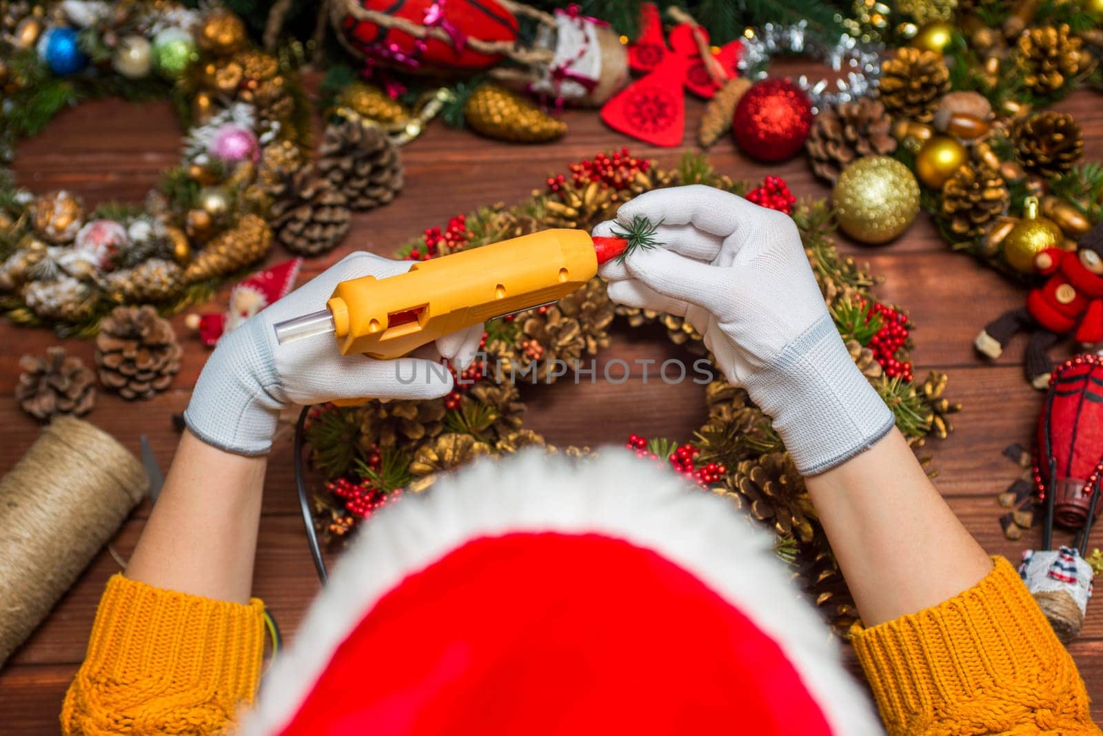 Creating a Christmas wreath with womens hands on a wooden background. Concept of preparation for Christmas and New Year. Decoration for the house for Christmas.