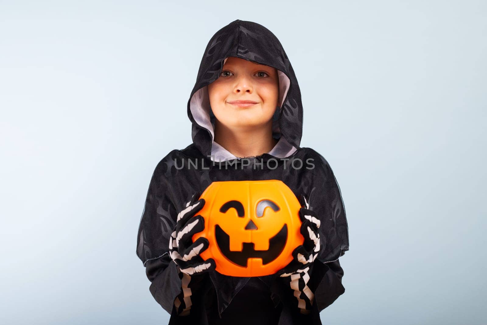 Happy Halloween. Cute little boy in a costume with a pumpkin basket jack-o-lantern.