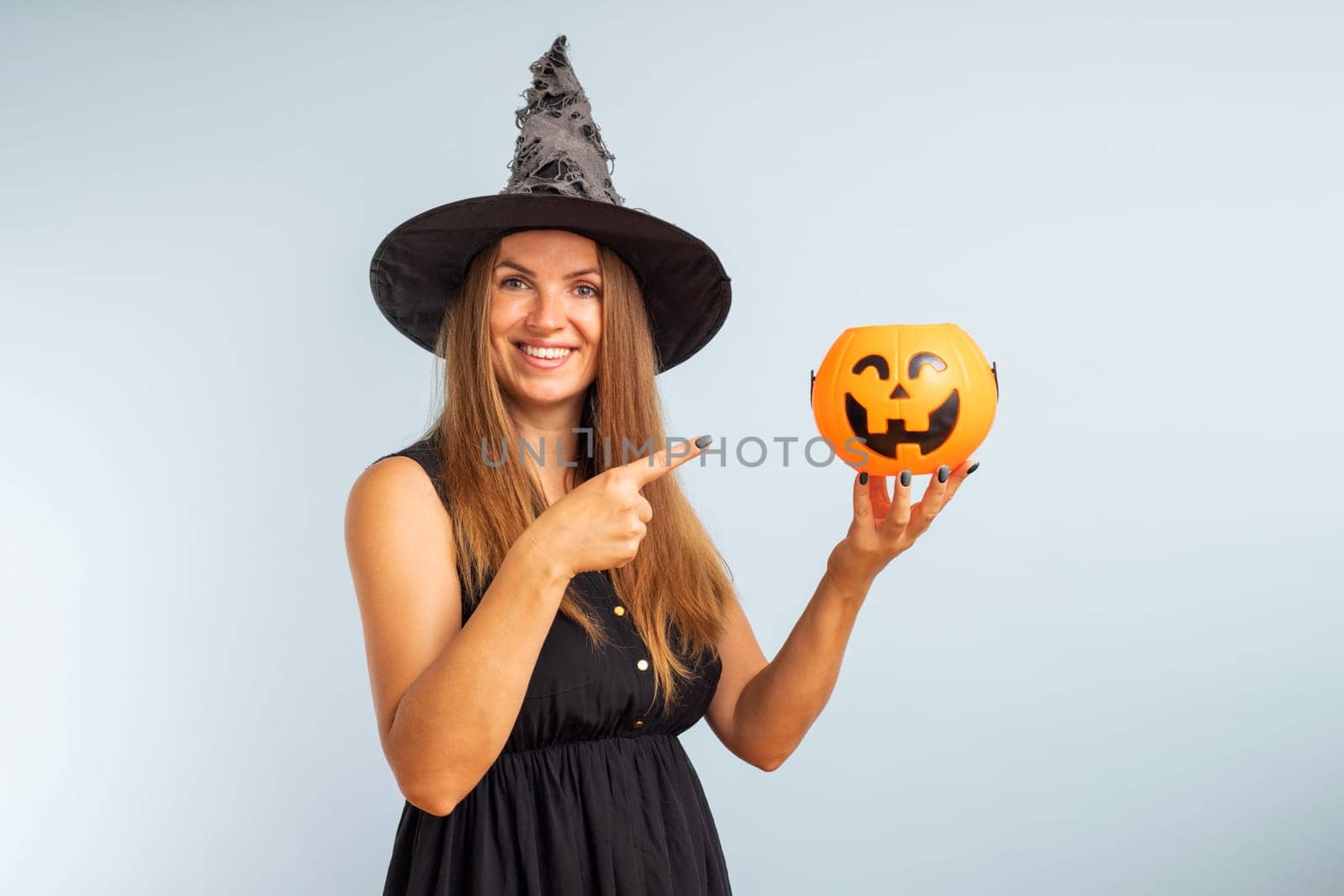 Happy woman in halloween witch costume with pumpkin basket jack-o-lantern by andreyz