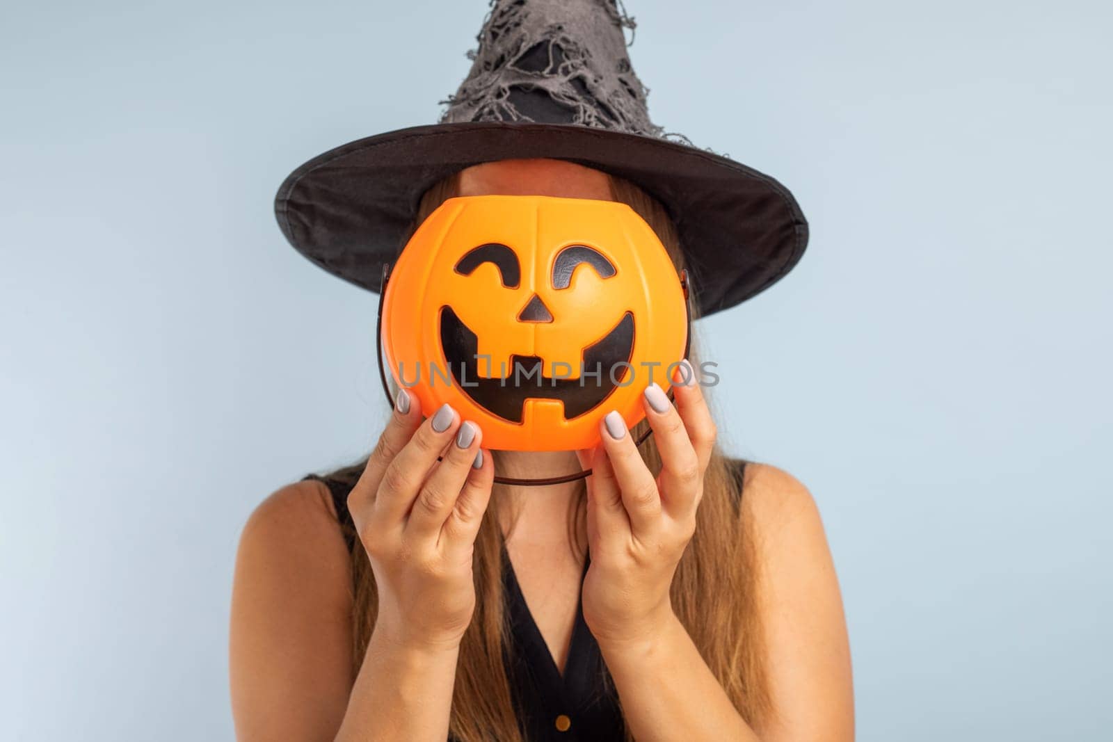 Happy Halloween. Happy young woman in halloween witch costume with pumpkin basket jack-o-lantern.