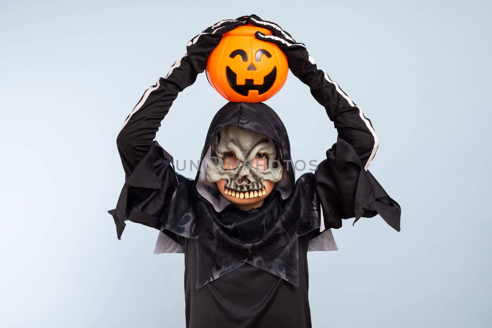 Happy Halloween. Cute little boy in a costume with a pumpkin basket jack-o-lantern.