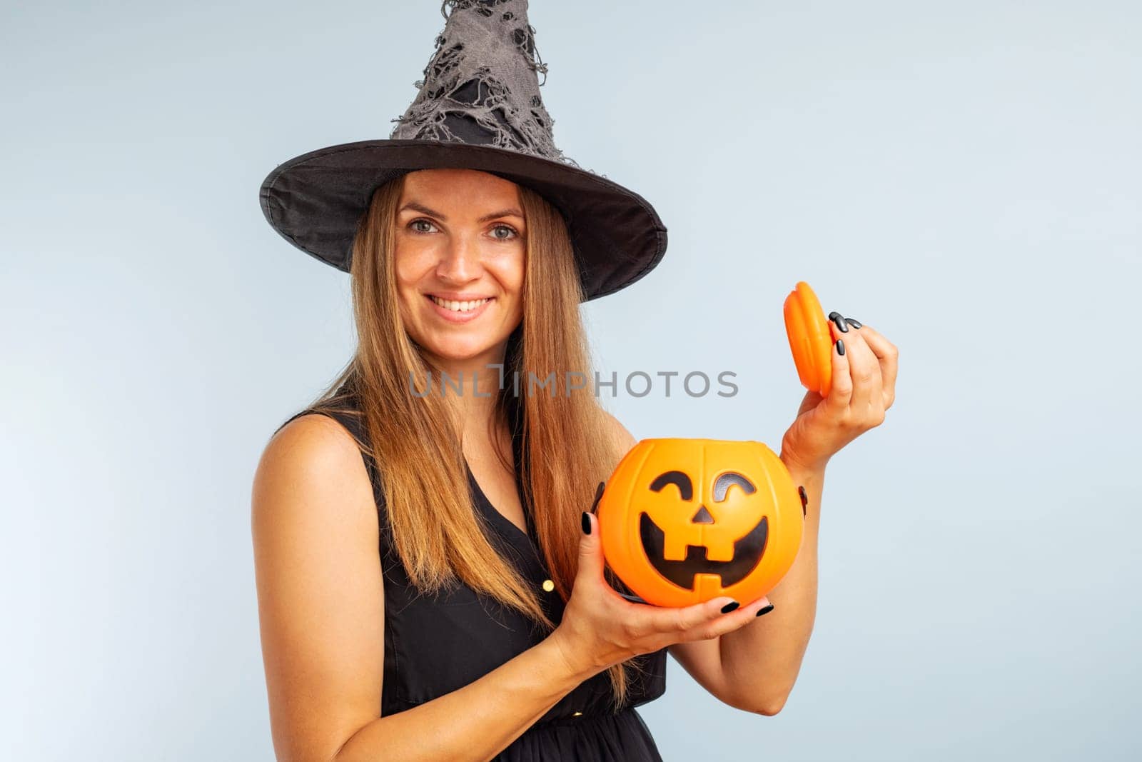 Happy Halloween. Happy young woman in halloween witch costume with pumpkin basket jack-o-lantern.