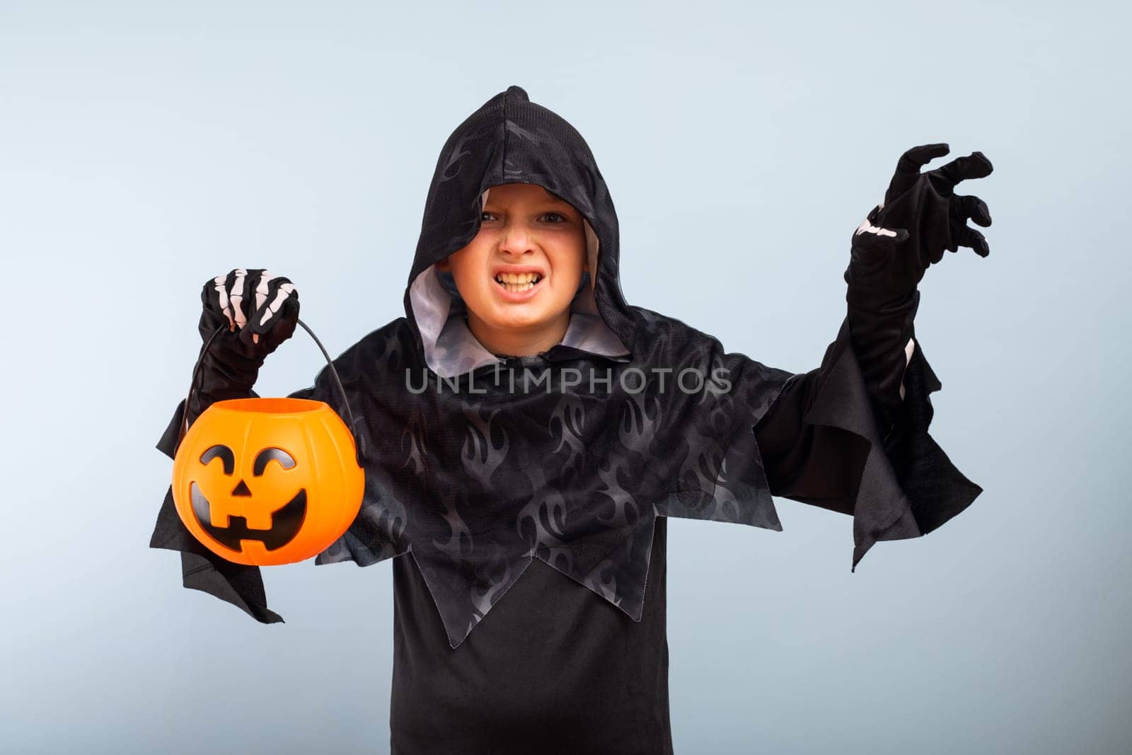Happy Halloween. Cute little boy in a costume with a pumpkin basket jack-o-lantern.