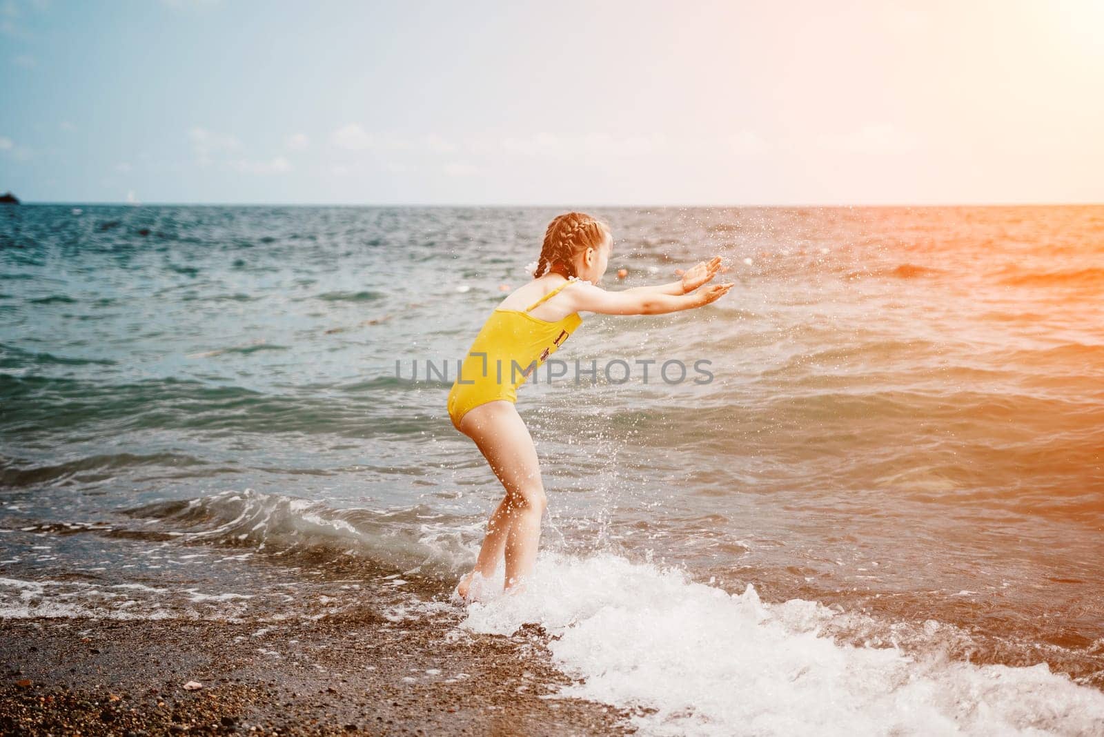 Cute little girl running along the seashore against a clear blue sea and rejoices in the rays of the summer sun. Beautiful girl in yellow swimsuit running and having fun on tropical beach. by panophotograph