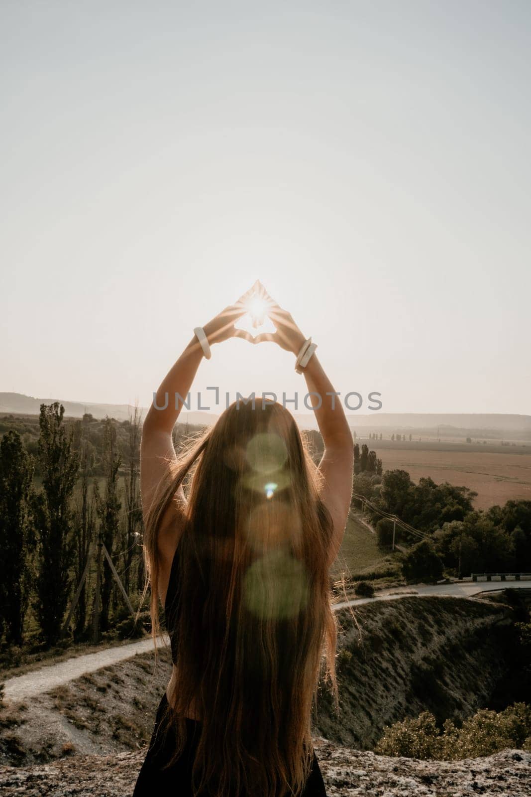 Well looking middle aged woman with long hair, fitness instructor in leggings and tops doing stretching and pilates on the rock near forest. Female fitness yoga routine concept. Healthy lifestyle.