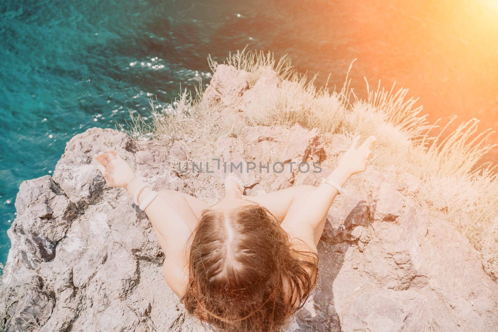 Woman sea yoga. Back view of free calm bliss satisfied woman with long hair standing on top rock with yoga position against of sky by the sea. Healthy lifestyle outdoors in nature, fitness concept. by panophotograph