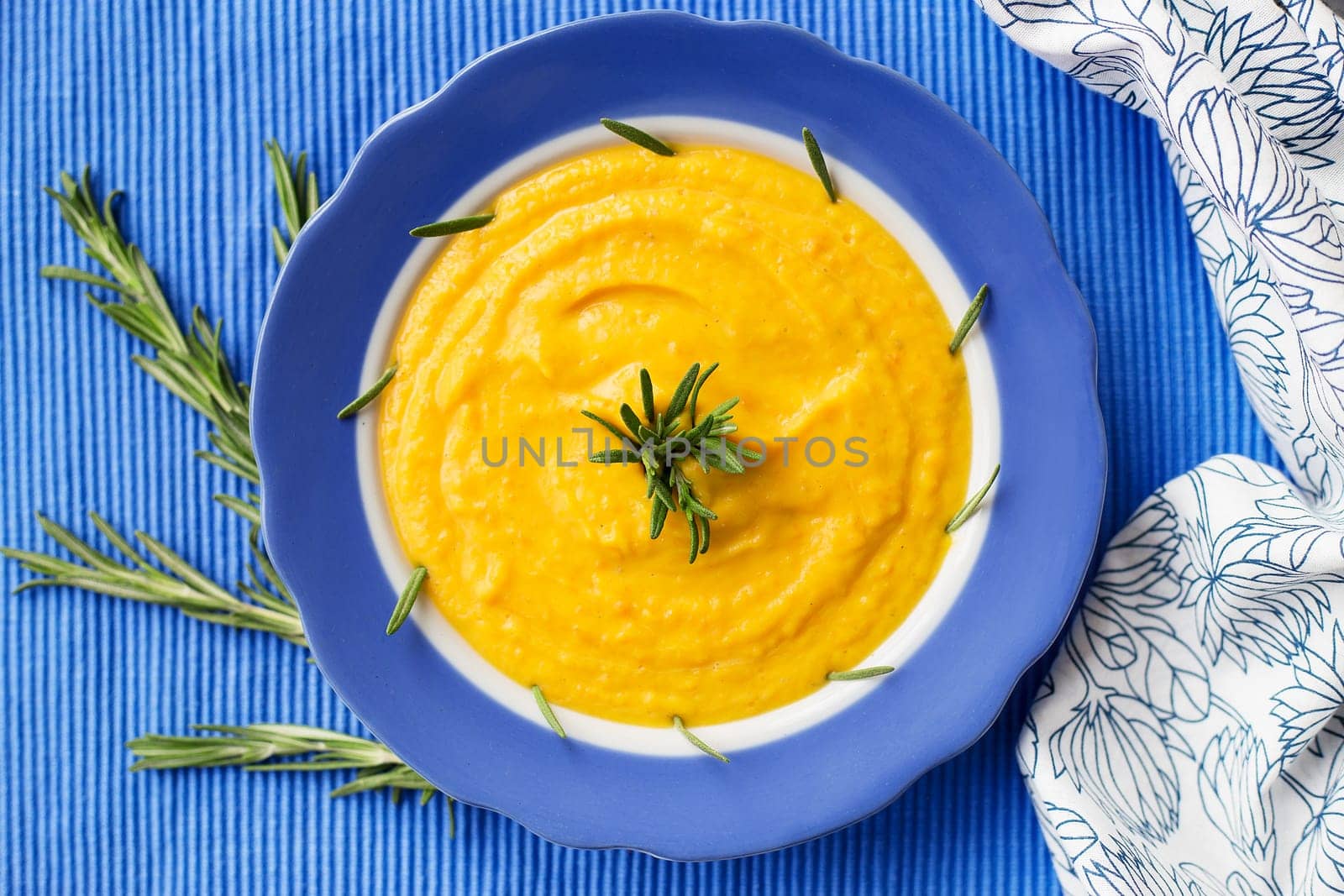 pumpkin cream soup in a blue plate on blue napkin, close-up