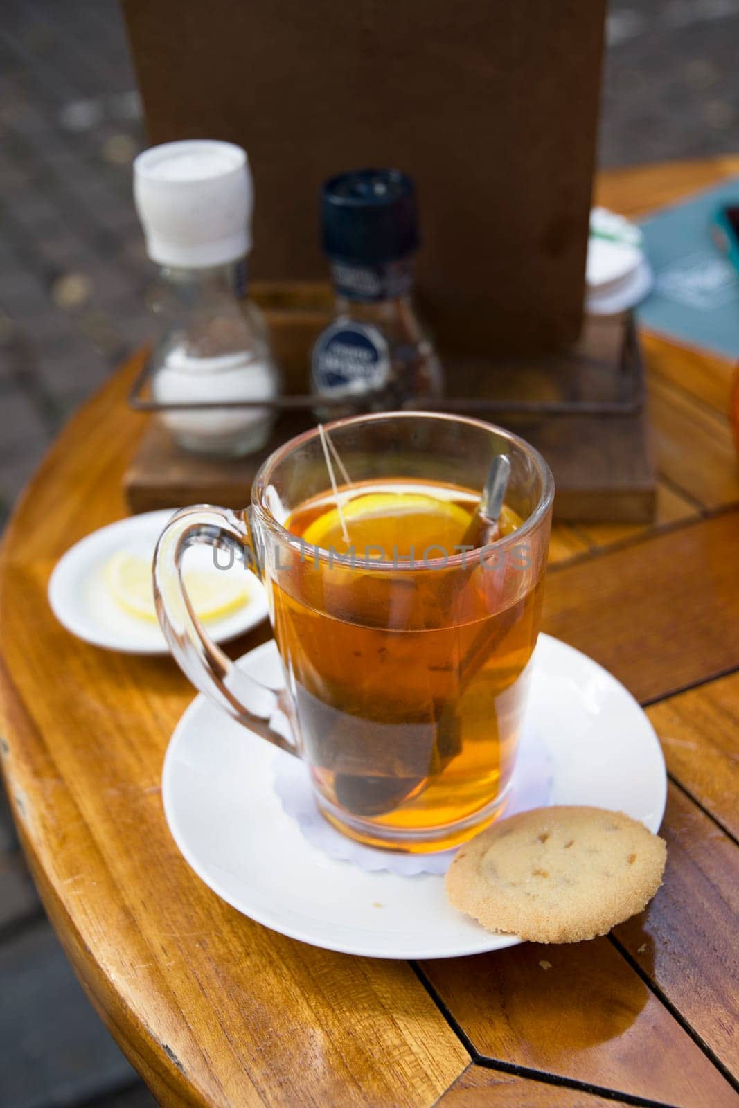 hot tea with lemon on a wooden table in a street cafe, relaxation in the city center, High quality photo