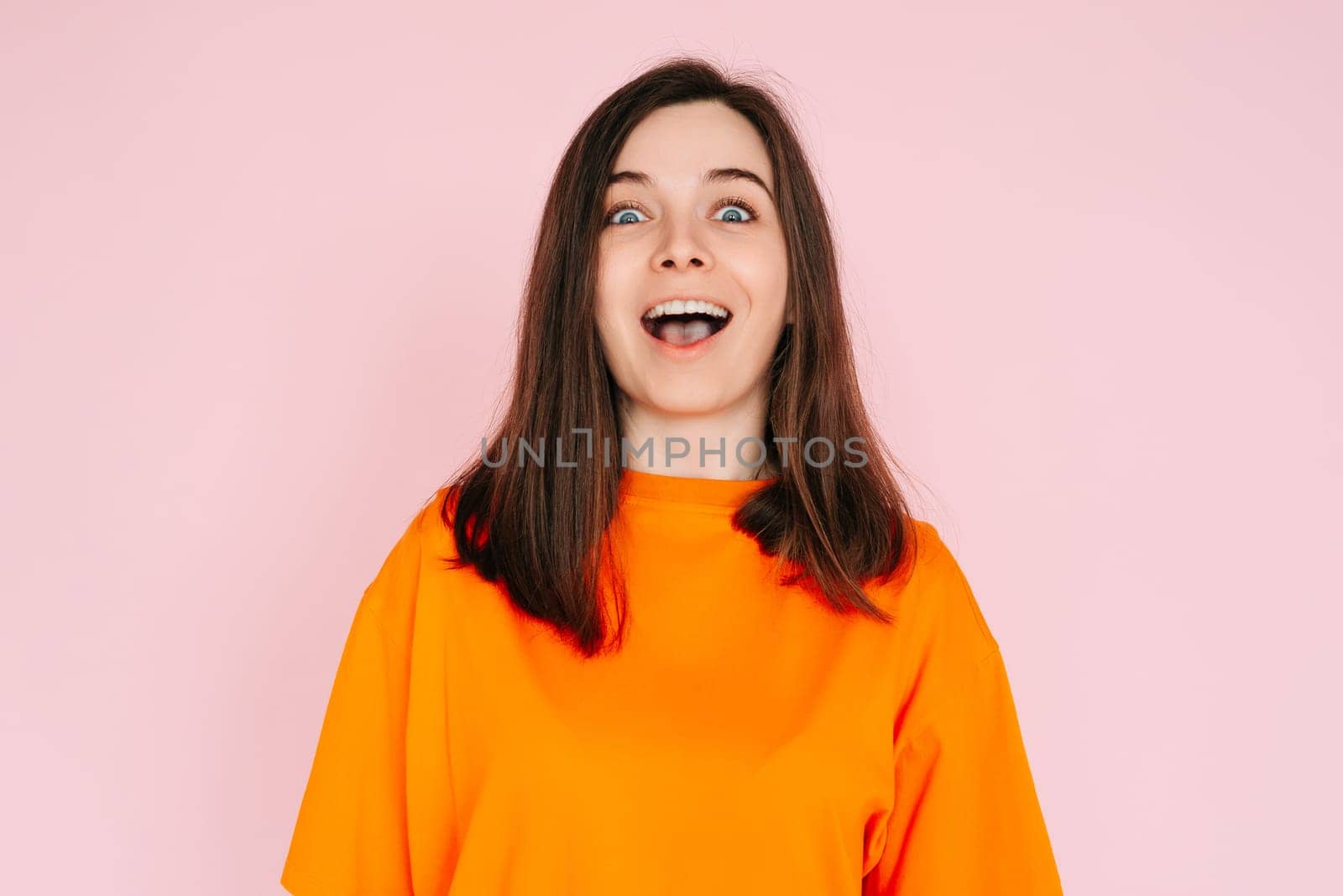 Energetic Expression: Impressed and Cheerful Woman with Open Mouth - Vibrant Emotion and Enthusiasm Captured on Pink Background