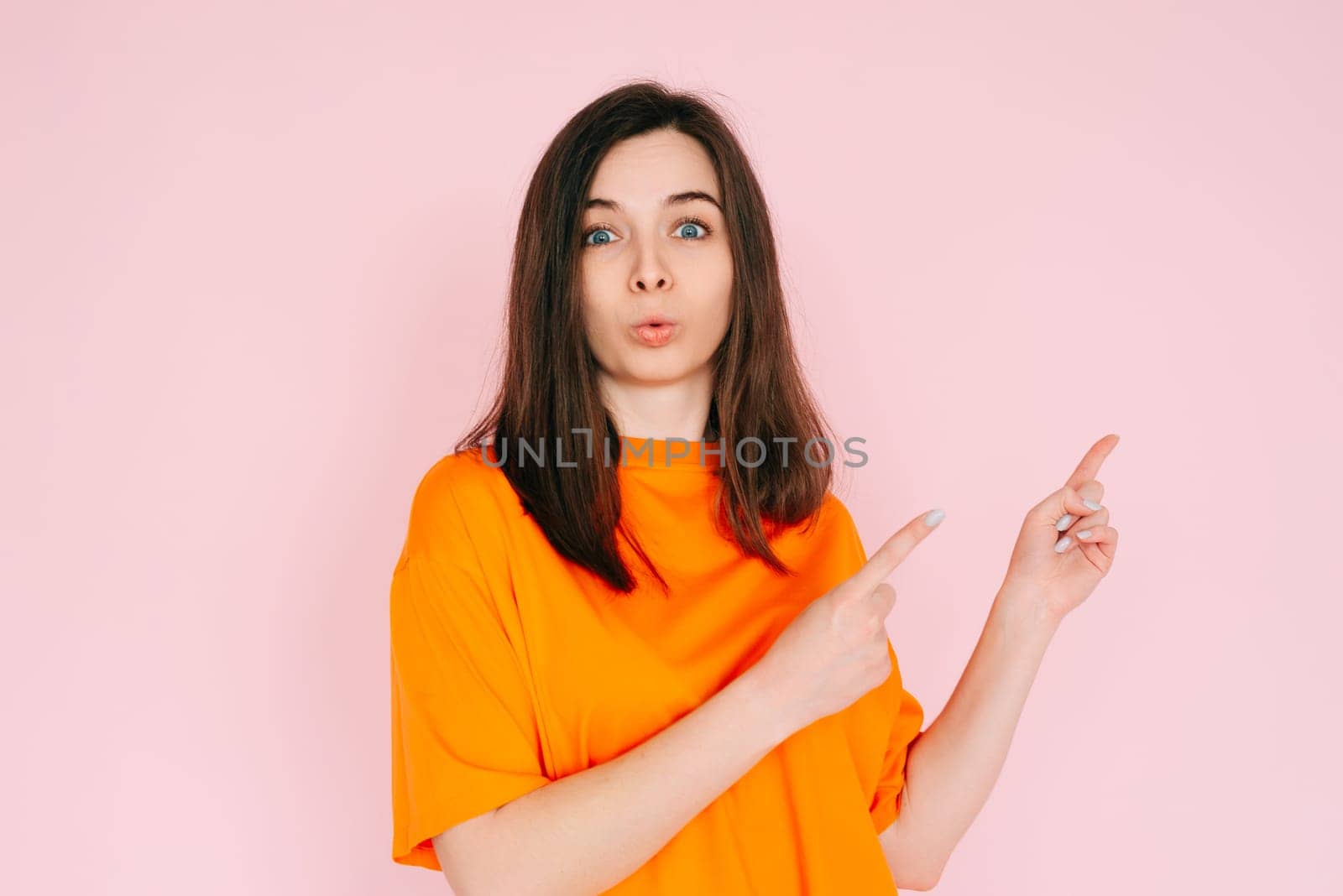 Playful Gesture: Humorous Woman Showing Two Fingers Pointing at Empty Space - Fun and Interaction Concept on Vibrant Pink Background