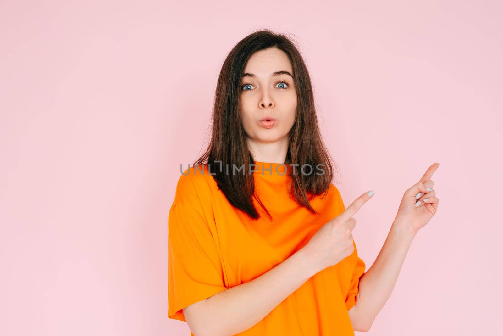 Engaging Playfulness: Humorous Woman Pointing Two Fingers at Empty Space - Interactive Concept with a Touch of Humor, Vibrant Pink Background.