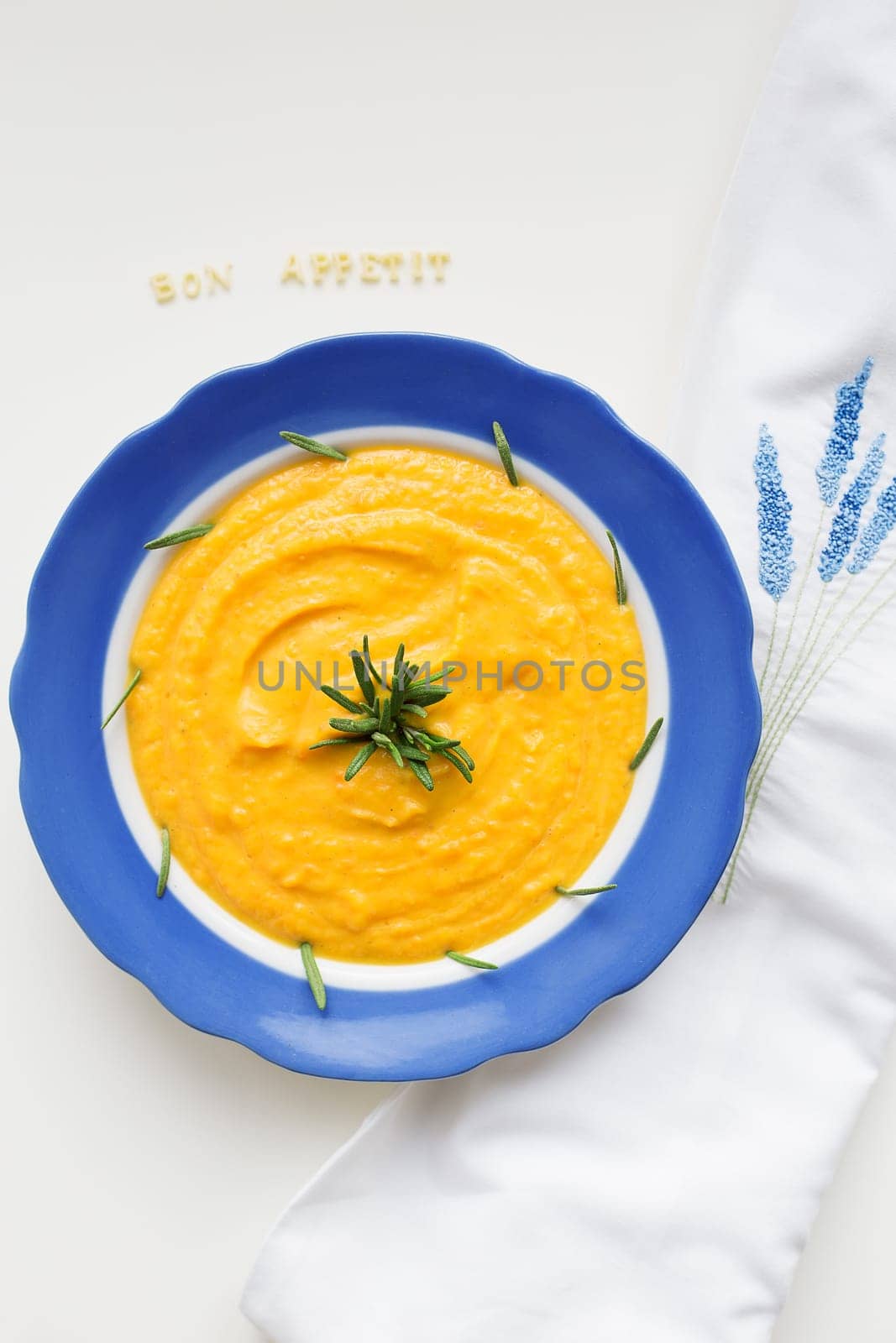 pumpkin soup in a blue plate on a napkin with flowers