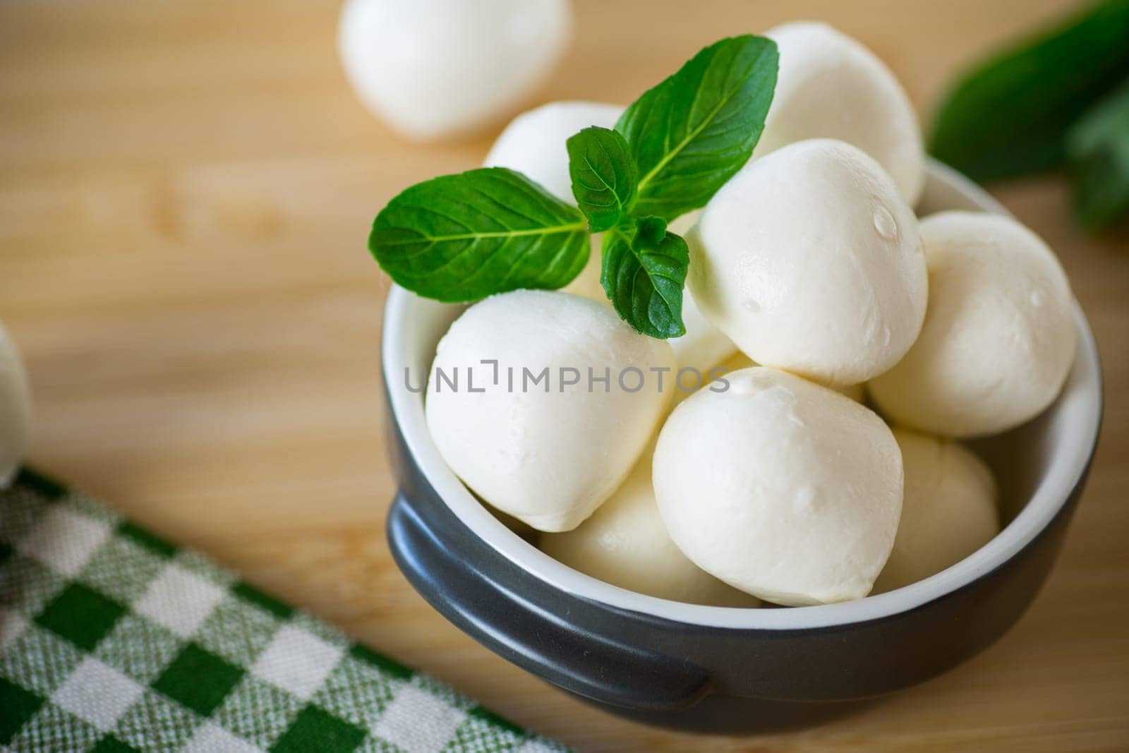 Small balls of traditional mozzarella in a ceramic bowl with mint