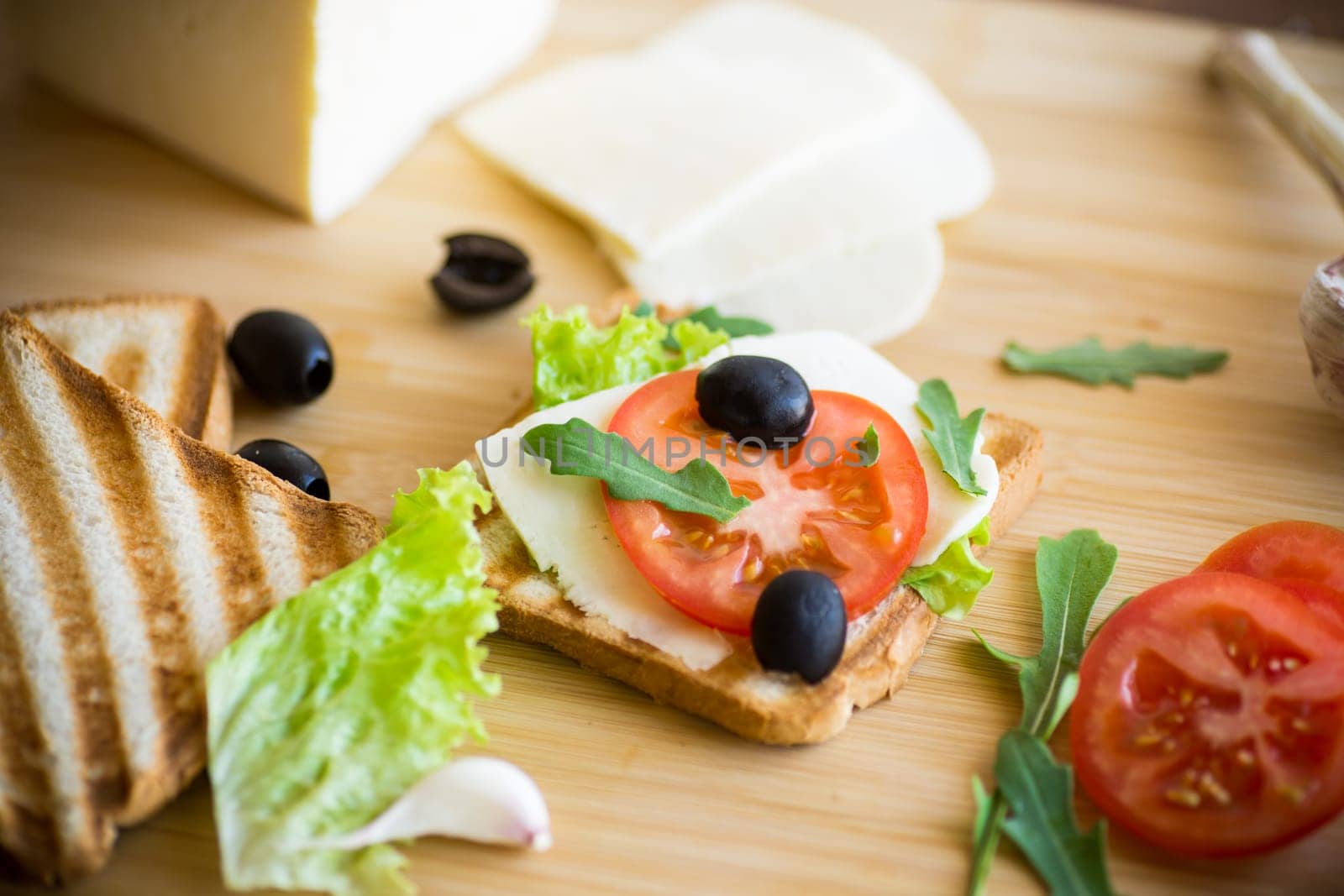 fried toasts with mozzarella, lettuce and tomatoes with herbs on a wooden table