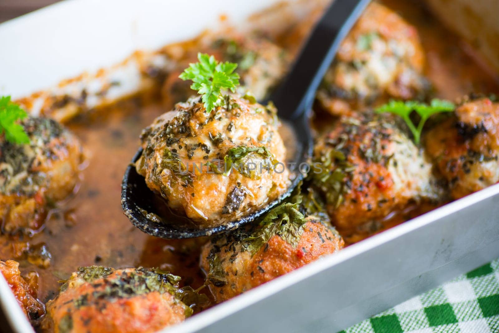 cooked meatballs from minced meat in a sauce in a ceramic form, on a wooden table