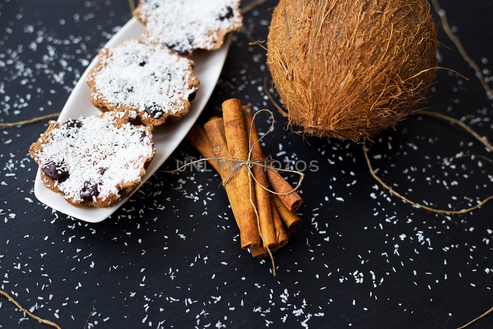 coconut muffins with chocolate and cinnamon on a black background and whole coconut