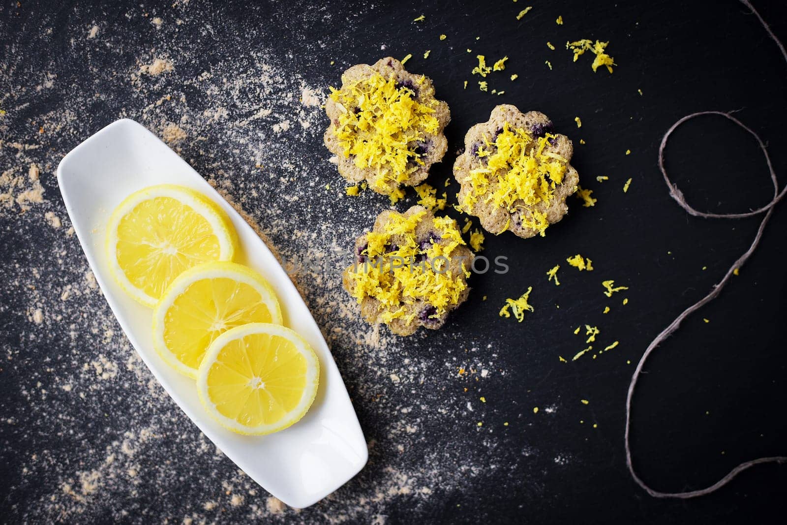 lemon cupcakes on a black background and a lemon on a plate