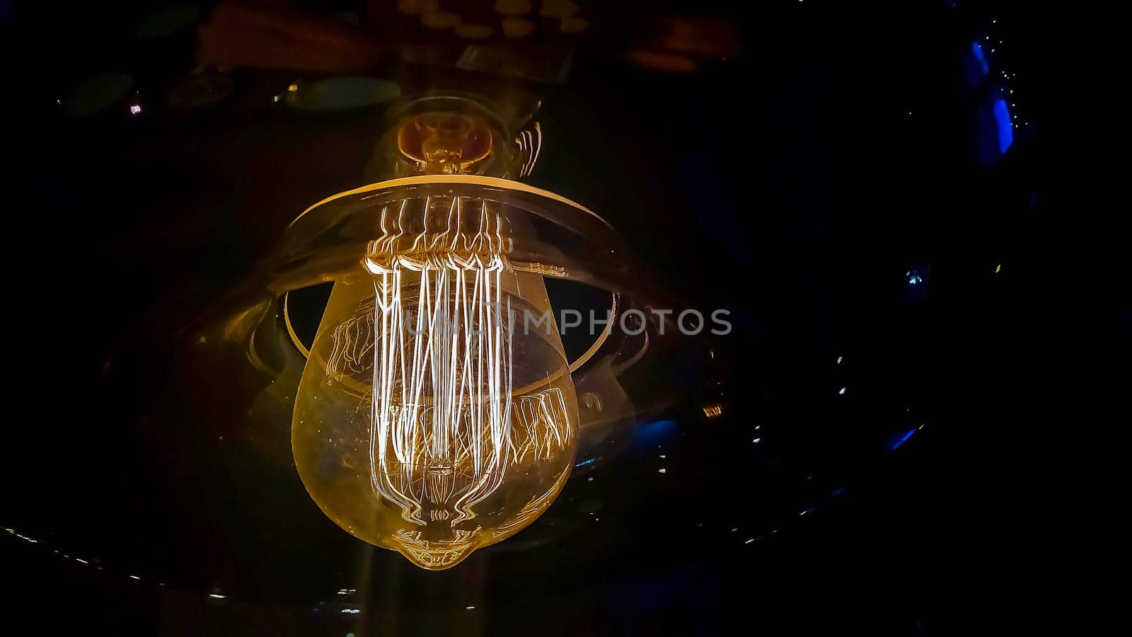 Vintage lightbulb on dark background with bright yellow shining wire