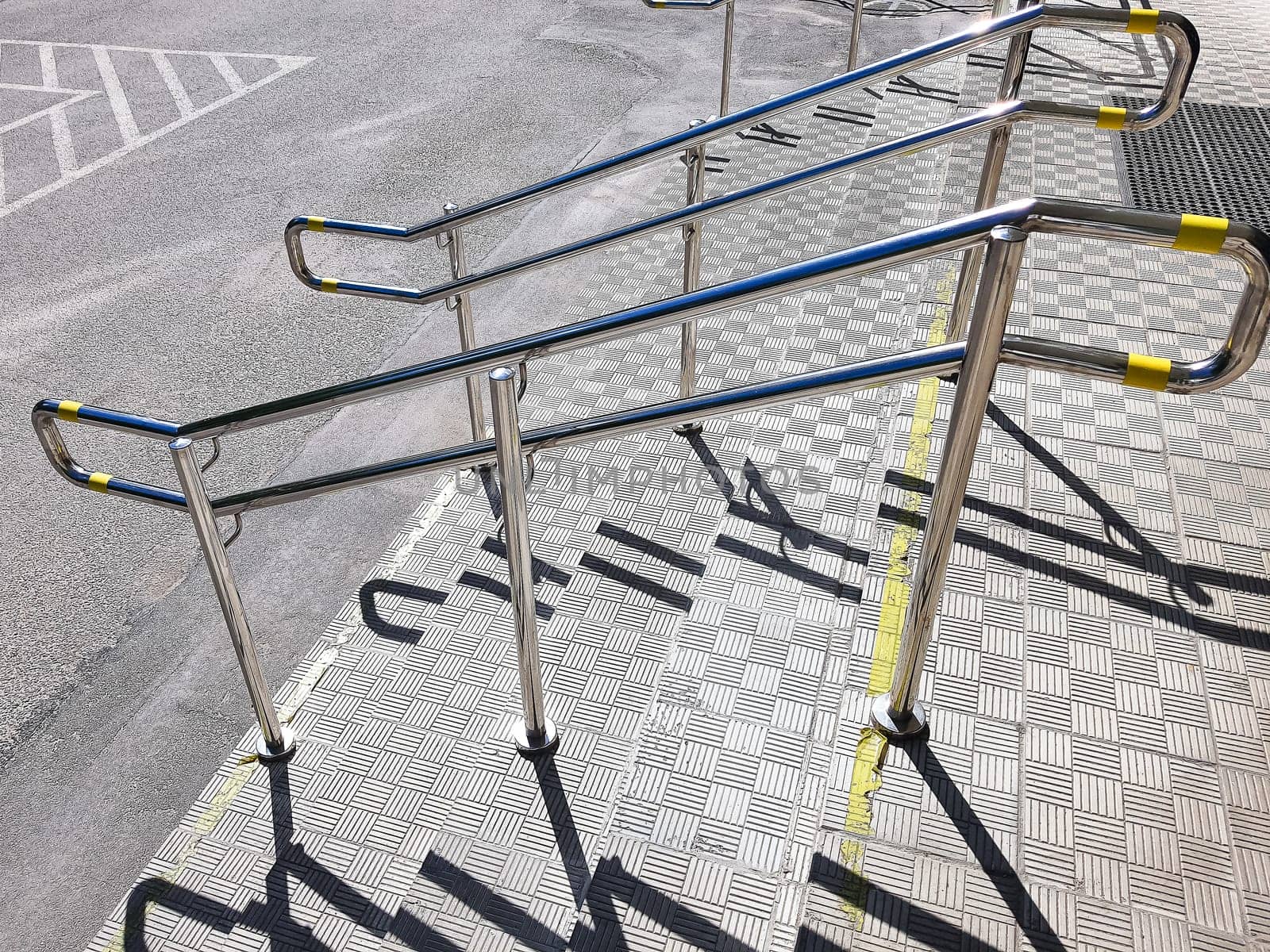 Handicapped symbol at parking space with Slope walkway for disabled people, people pushing strollers, carts with stainless bars to prevent falling.
