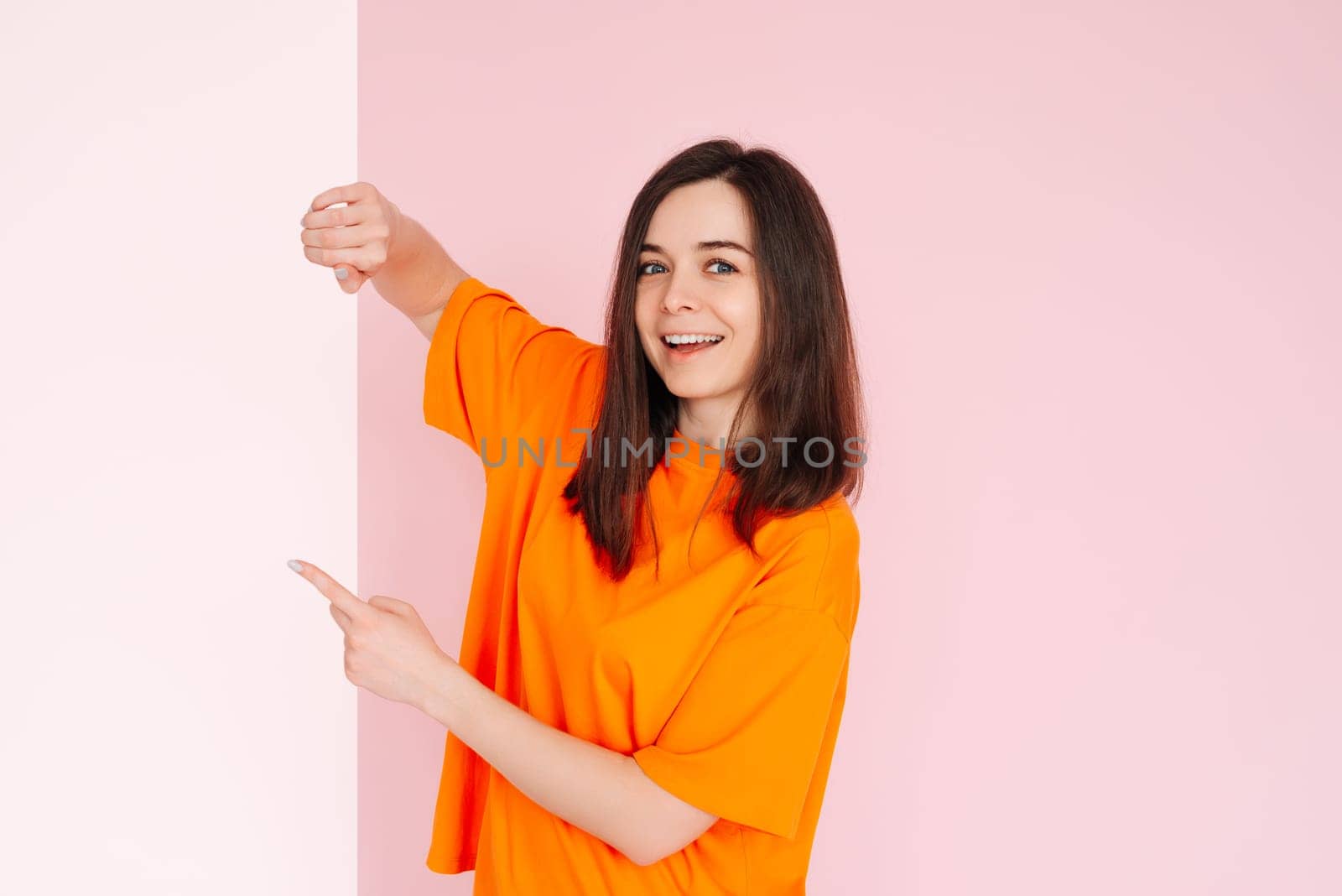 Affordable Deals: Optimistic Girl Holding Paper Board with Empty Space - Presentation of Cheap Prices for Advertising, Isolated on Pink Background