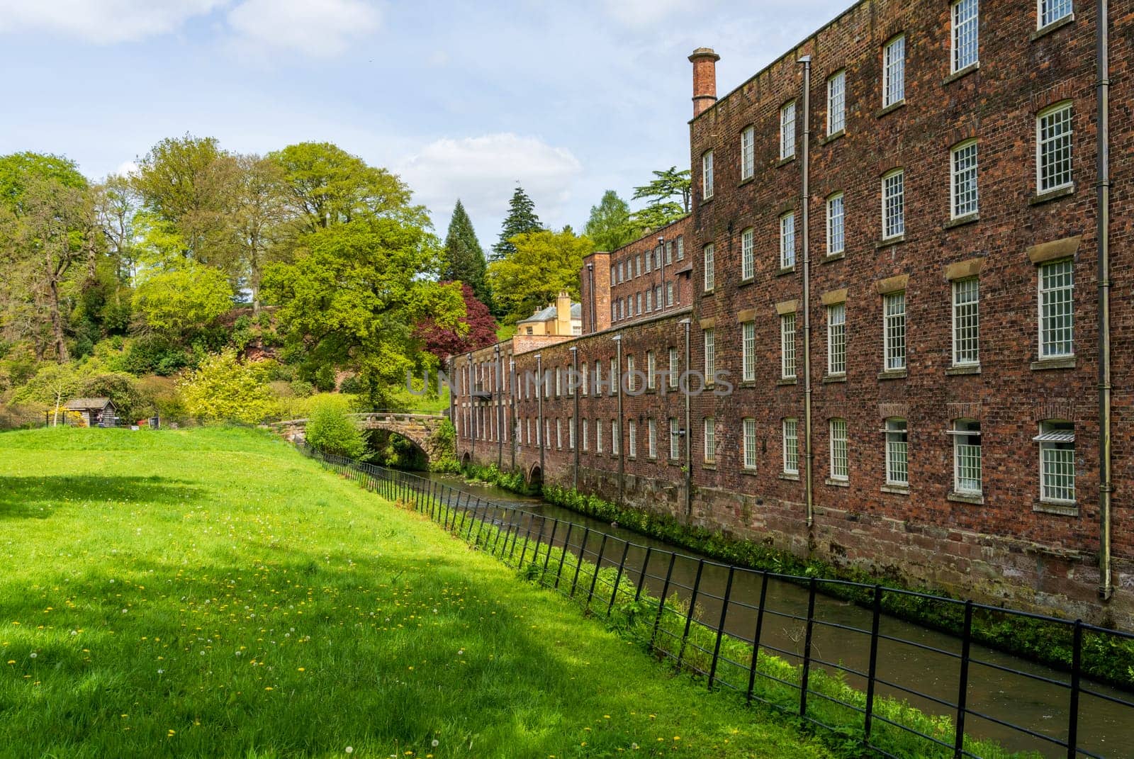 Exterior of restored cotton spinning and weaving mill in north of England with river