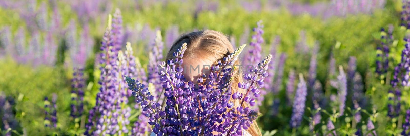 Girl with a bouquet in the hands.portrait of cute little happy seven year old kid girl with bloom flowers lupines