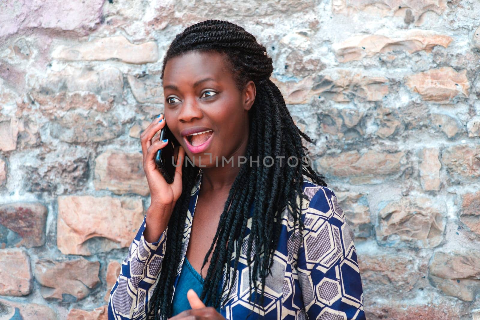 African american young adult woman holding mobile phone listening good vibes message and news , smiling. by verbano