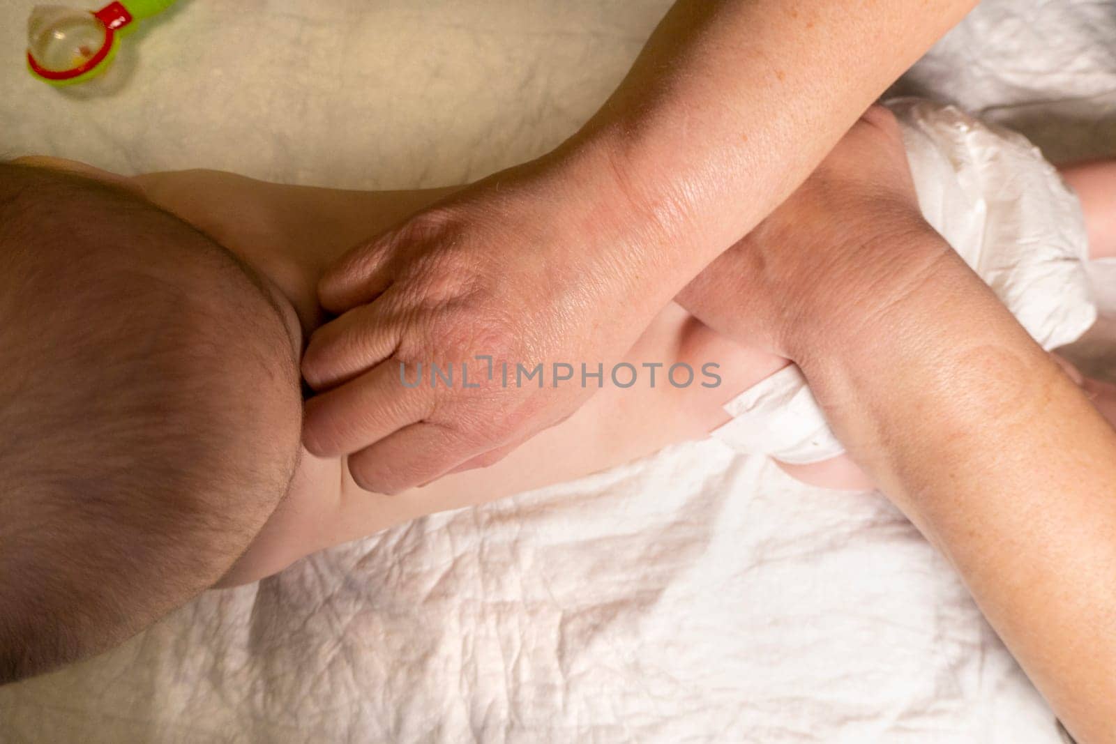 baby back massage. The hands of an adult - a mother or a masseur - massage a little girl. Dark background