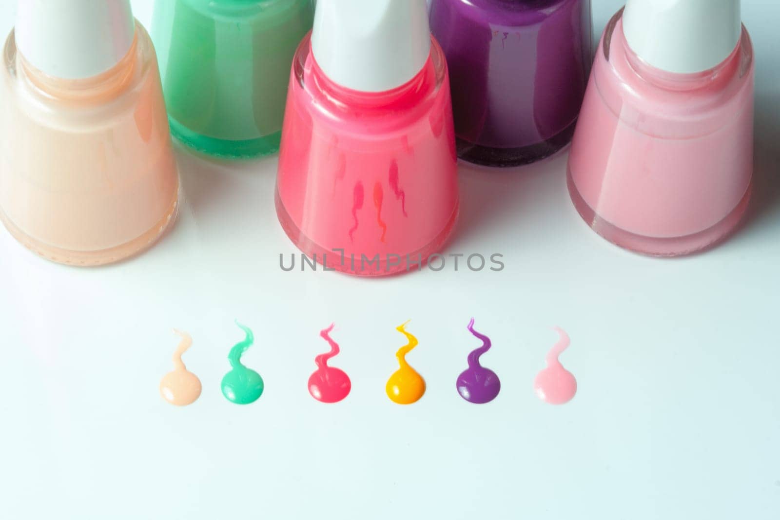 Bottles with spilled nail polish over white background