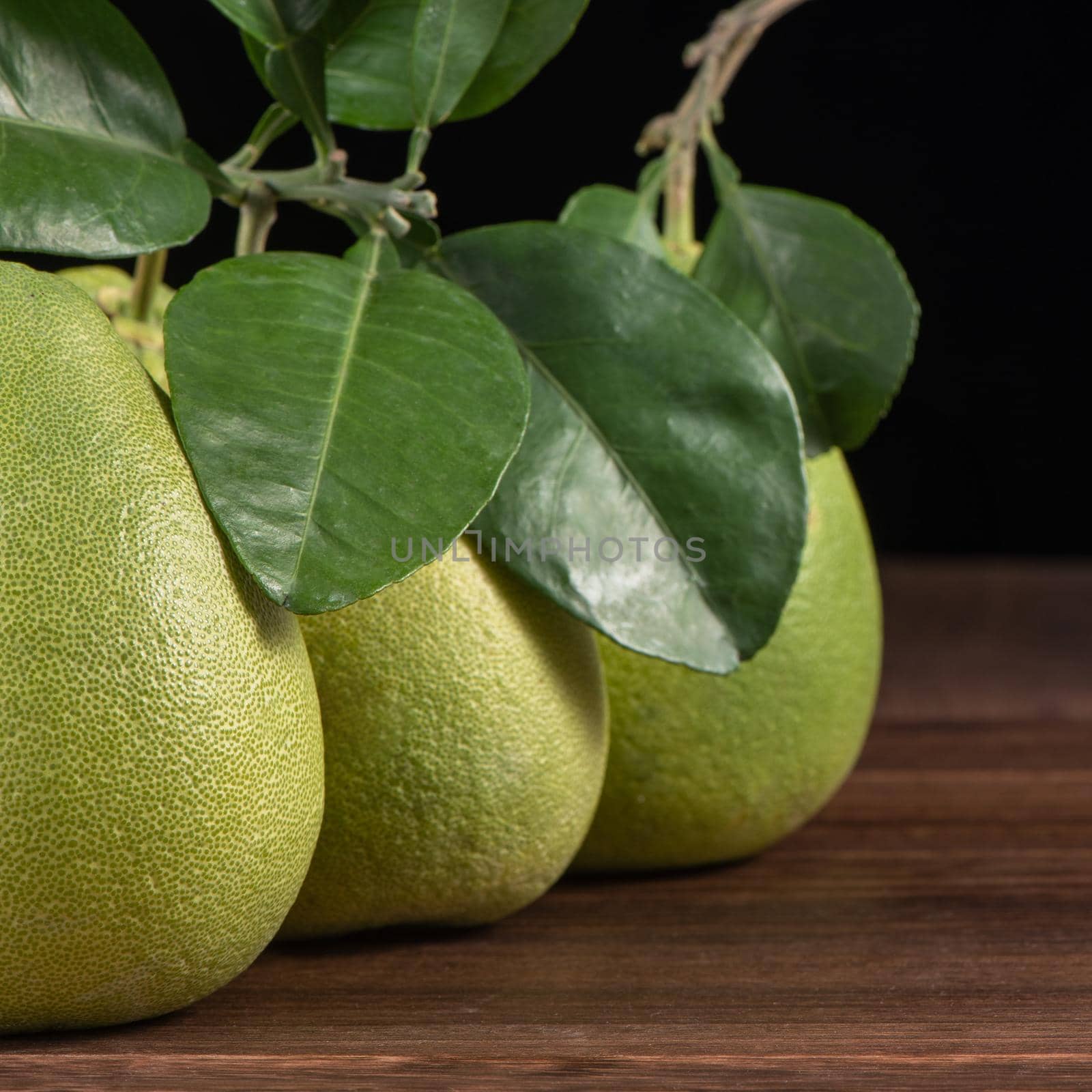 Fresh peeled pomelo, grapefruit, shaddock with green leaves on dark wooden plank table. Seasonal fruit near mid-autumn festival, close up, copy space