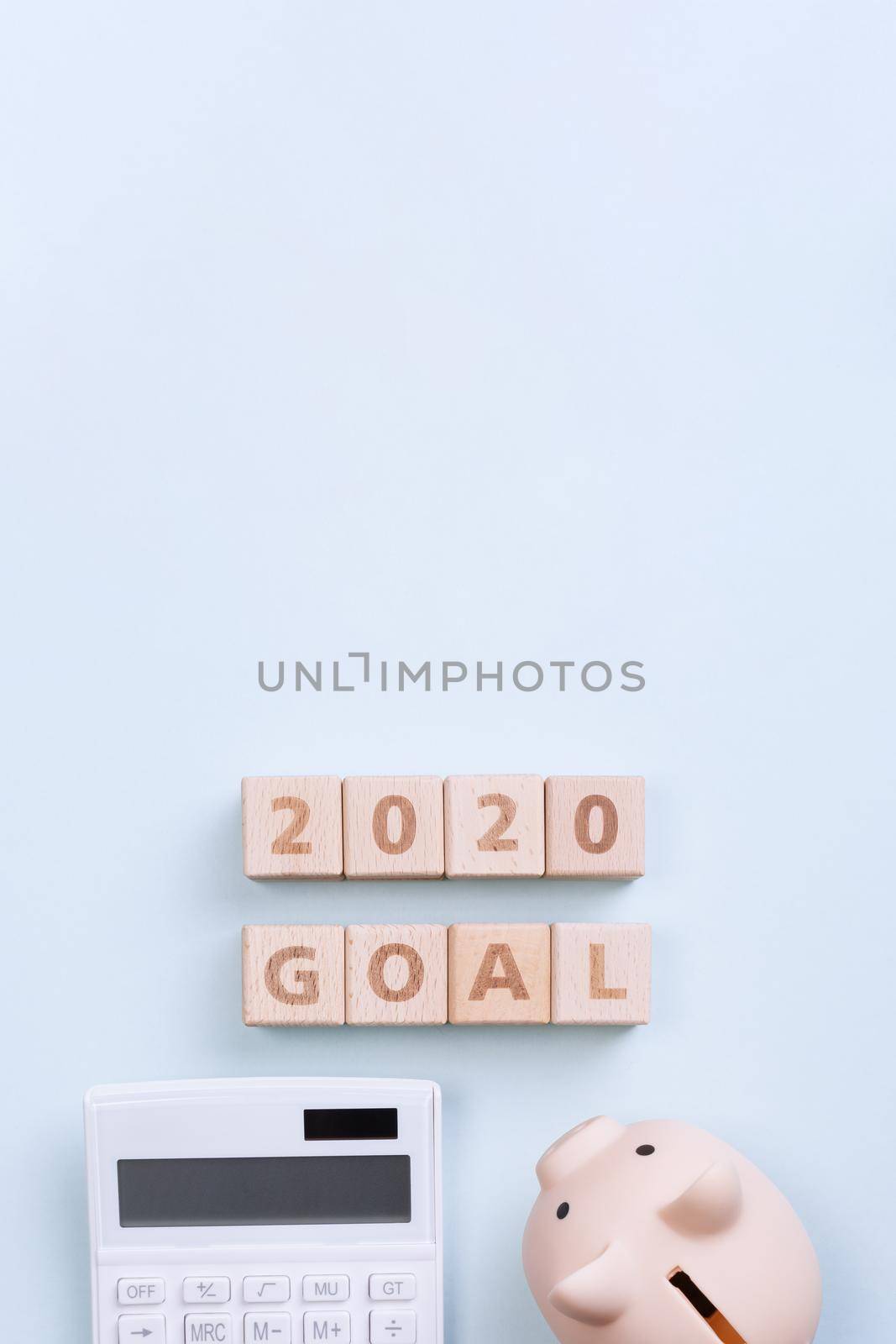 2020 goal, finance plan abstract design concept, wood blocks on blue table background with piggy bank and calculator, top view, flat lay, copy space.