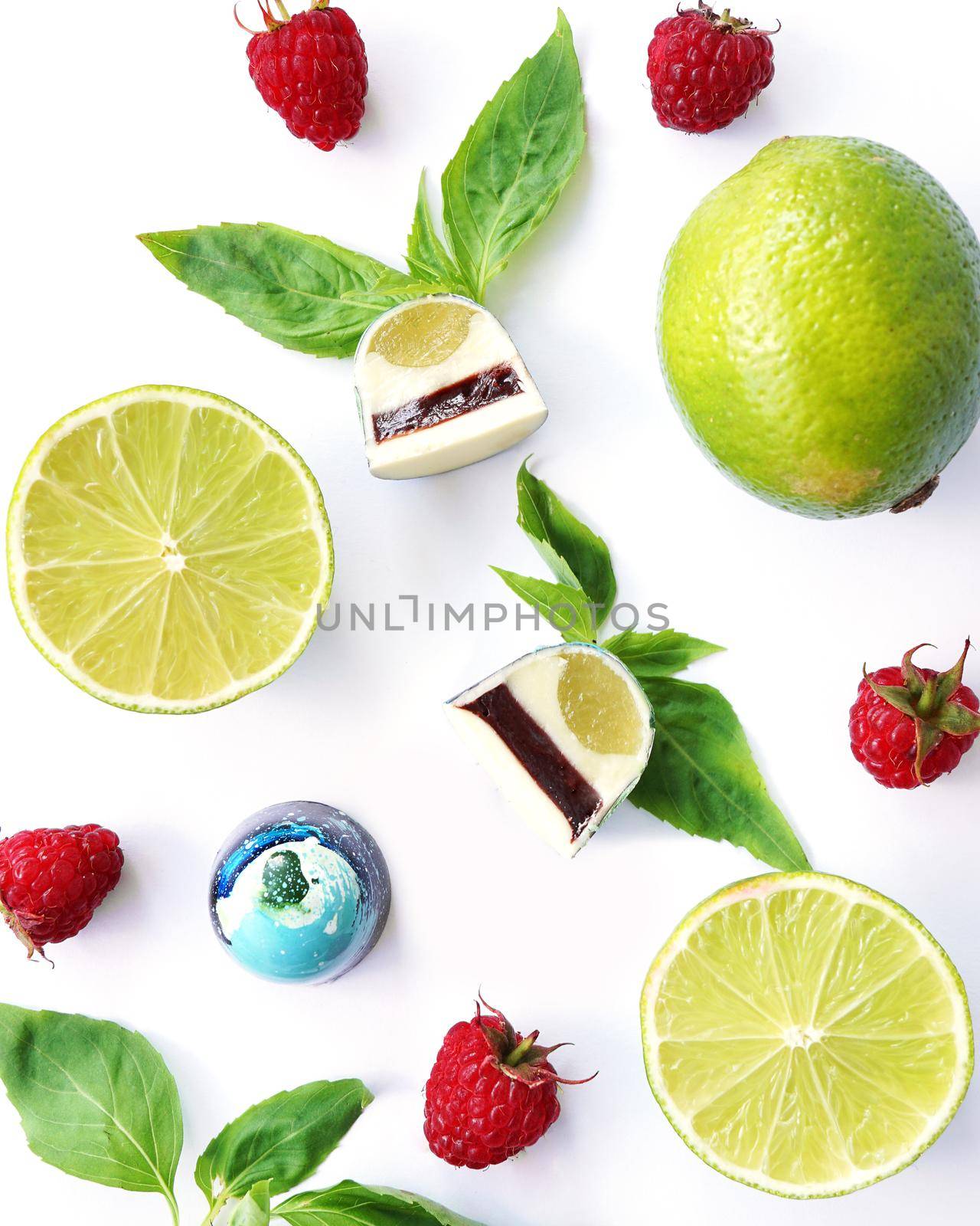Cutaway chocolate candy. Raspberry, lime and basil on a white background. Handmade sweets. Top View