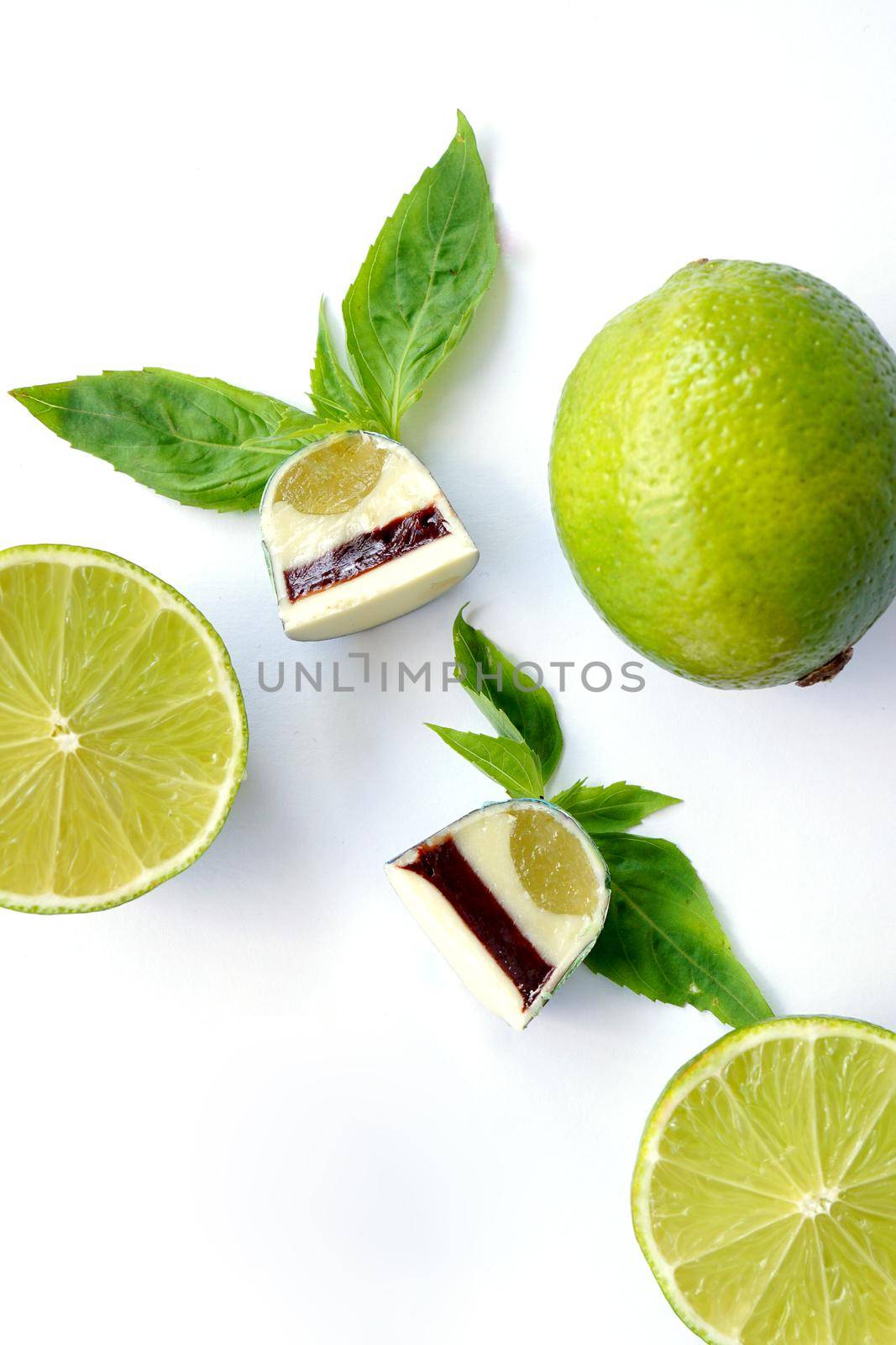 Cutaway chocolate candy. Lime and basil on a white background. Handmade sweets. Top View