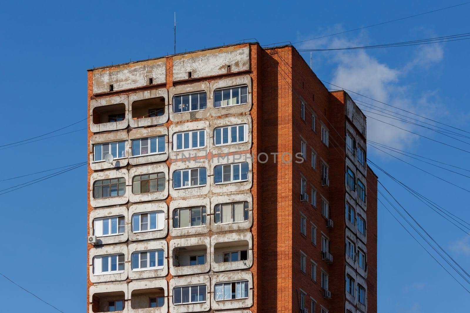 typical mid-russian concrete and brick high rise tower condominium residential building on blue sky background.