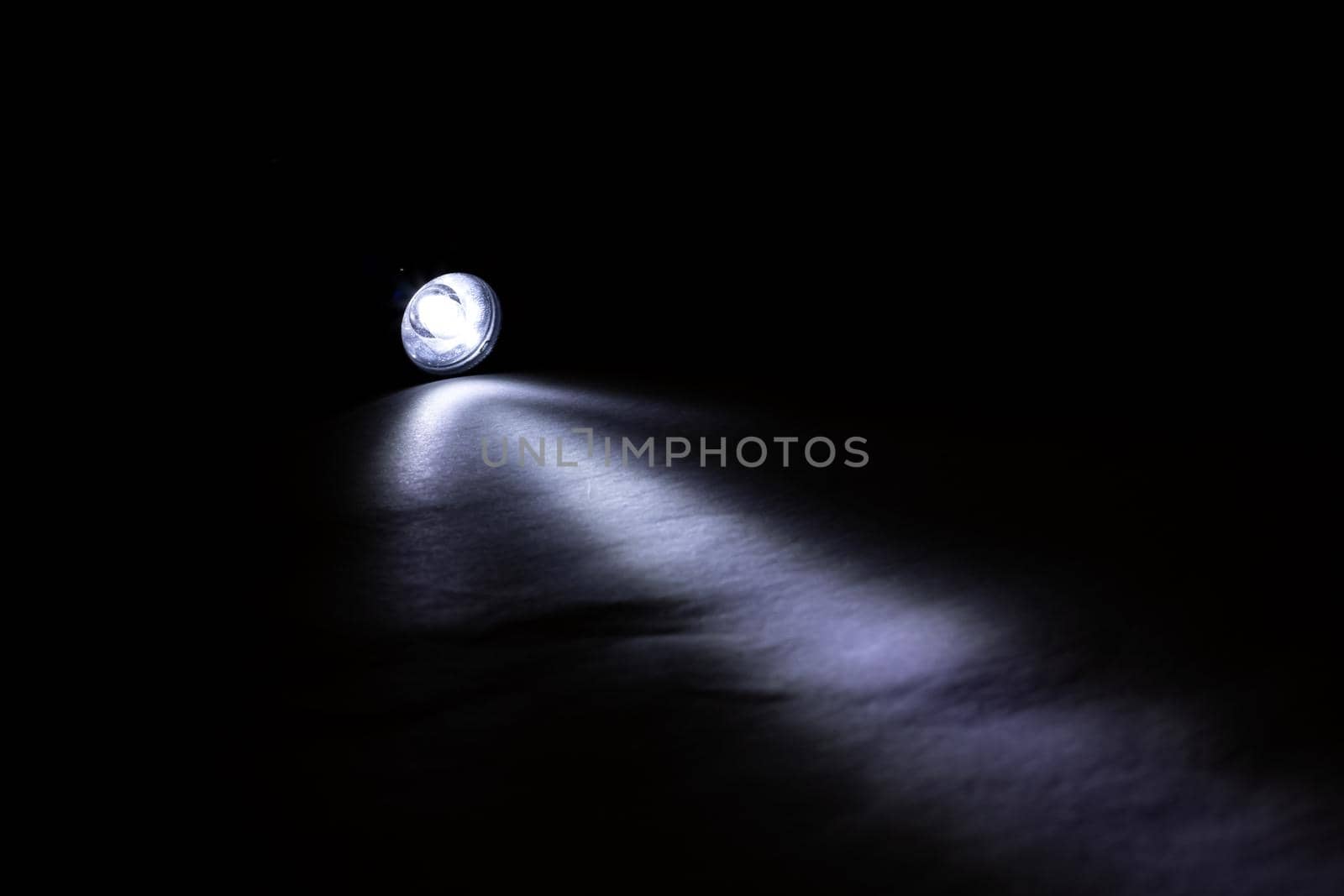 Blue light of a flashlight in the dark close up
