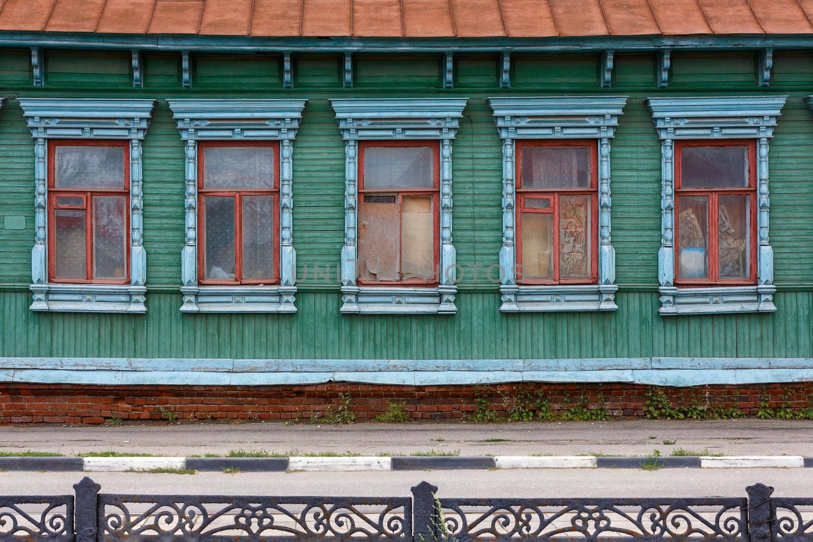 classic russian wooden house with 5 windows on it, front view poor condition on city street