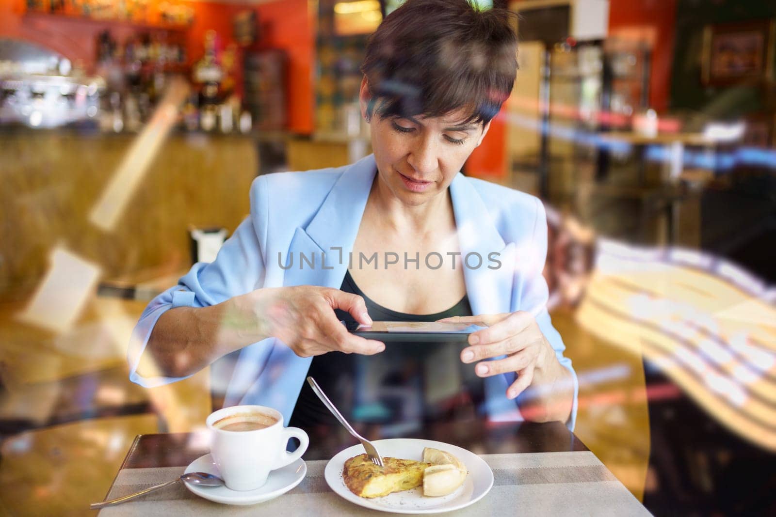 Young woman taking photo of dish with smartphone by javiindy