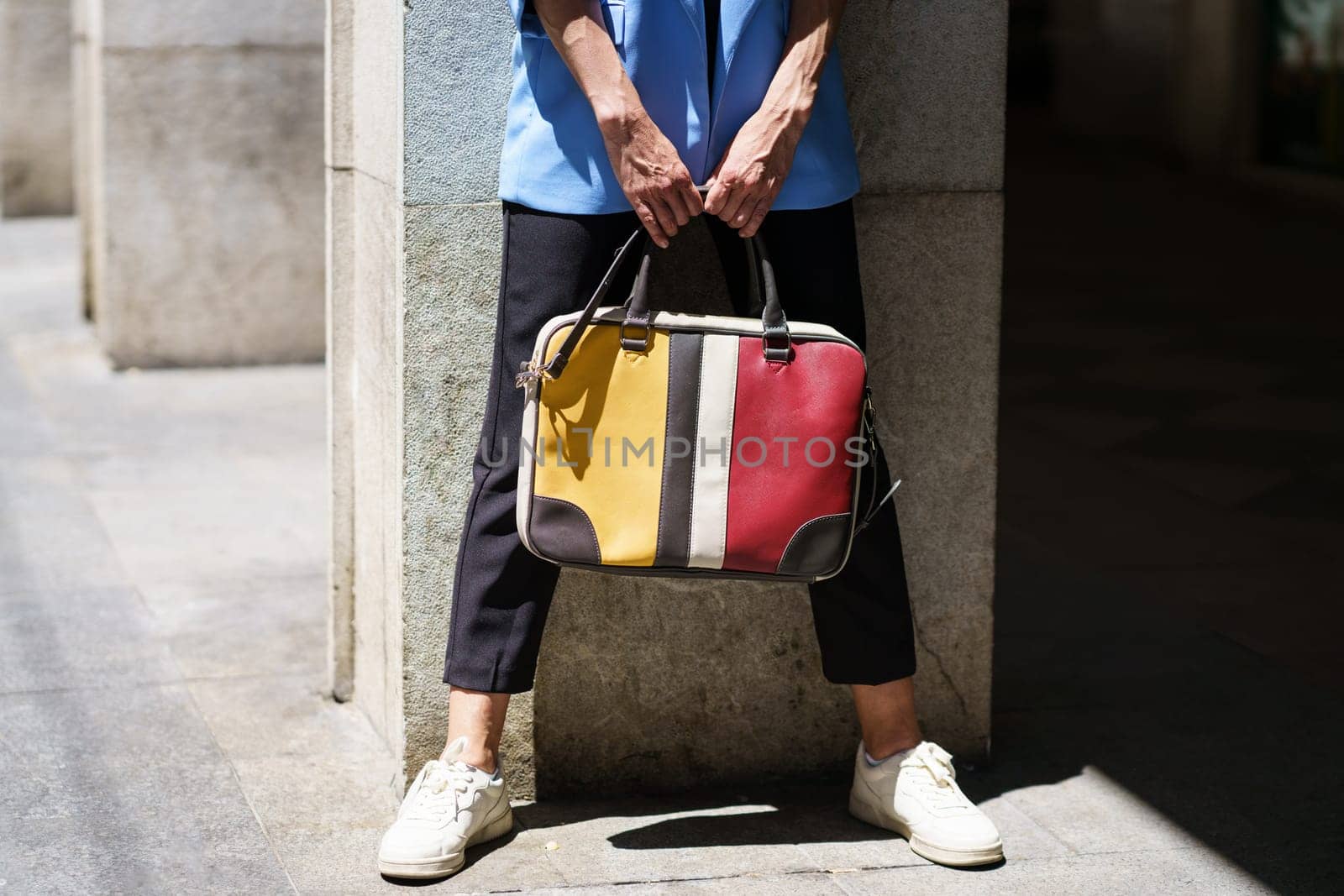 Faceless woman with colorful handbag on street by javiindy