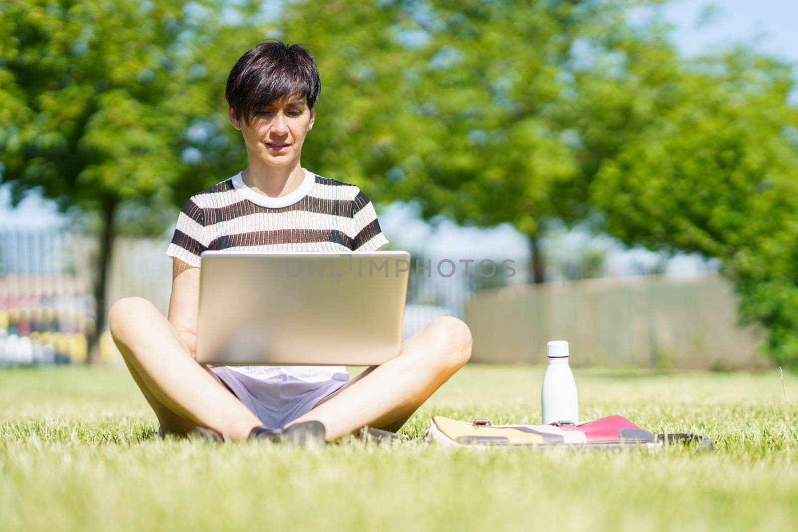 Woman working on laptop in park by javiindy