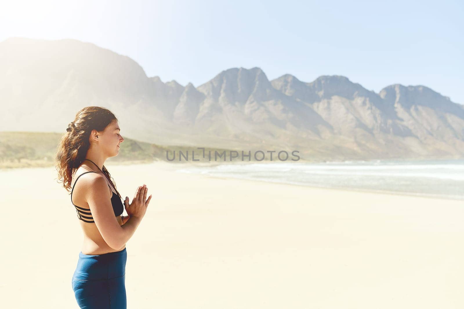I make it a priority to practice yoga regularly. a beautiful young woman practising yoga on the beach. by YuriArcurs