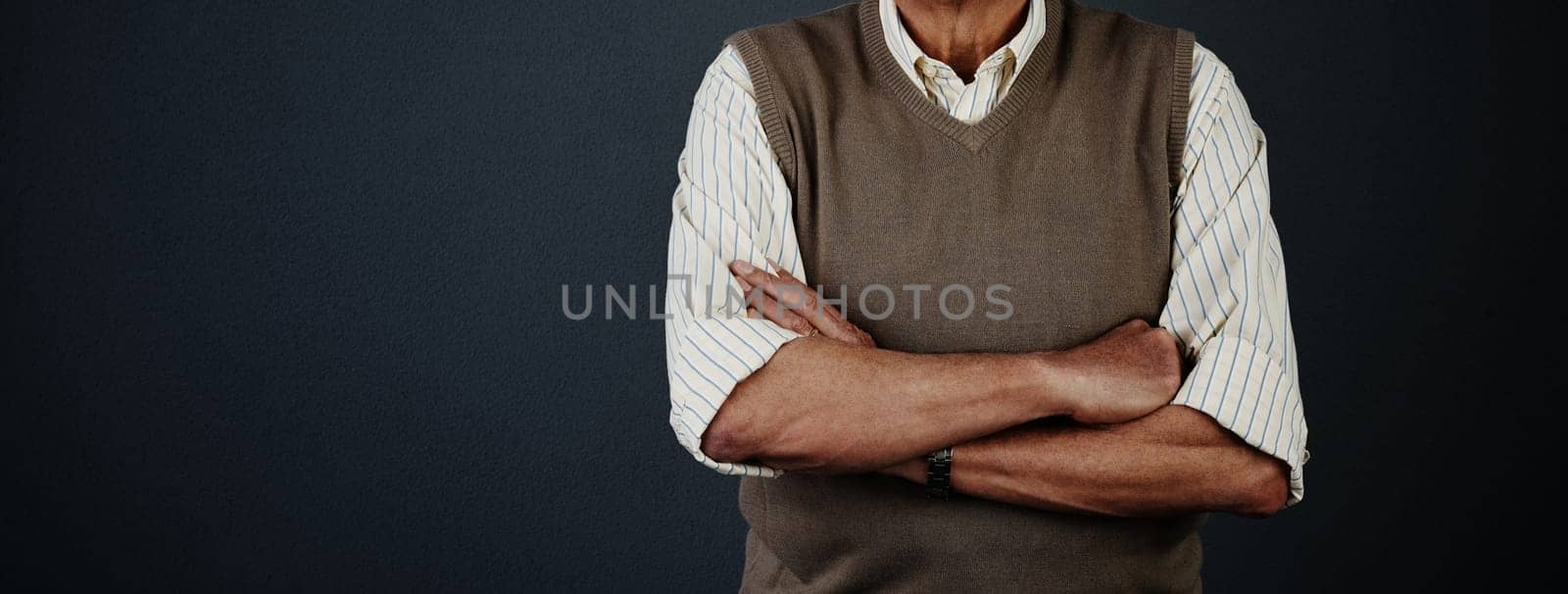 Ready and waiting. Studio shot of an unrecognizable man posing with his arms crossed against a dark background. by YuriArcurs