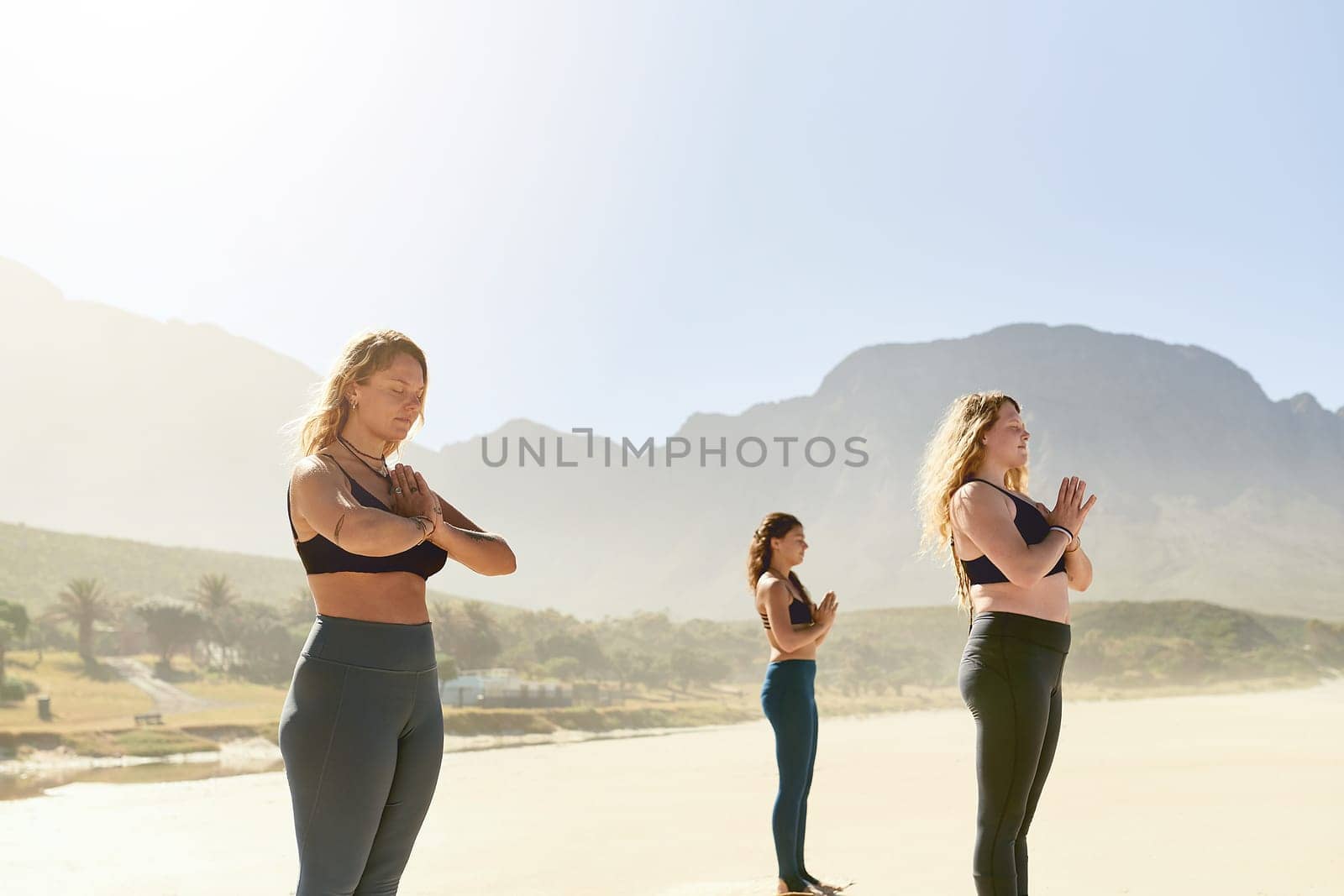 Yoga help you to live in the present. three young women practicing yoga on the beach. by YuriArcurs