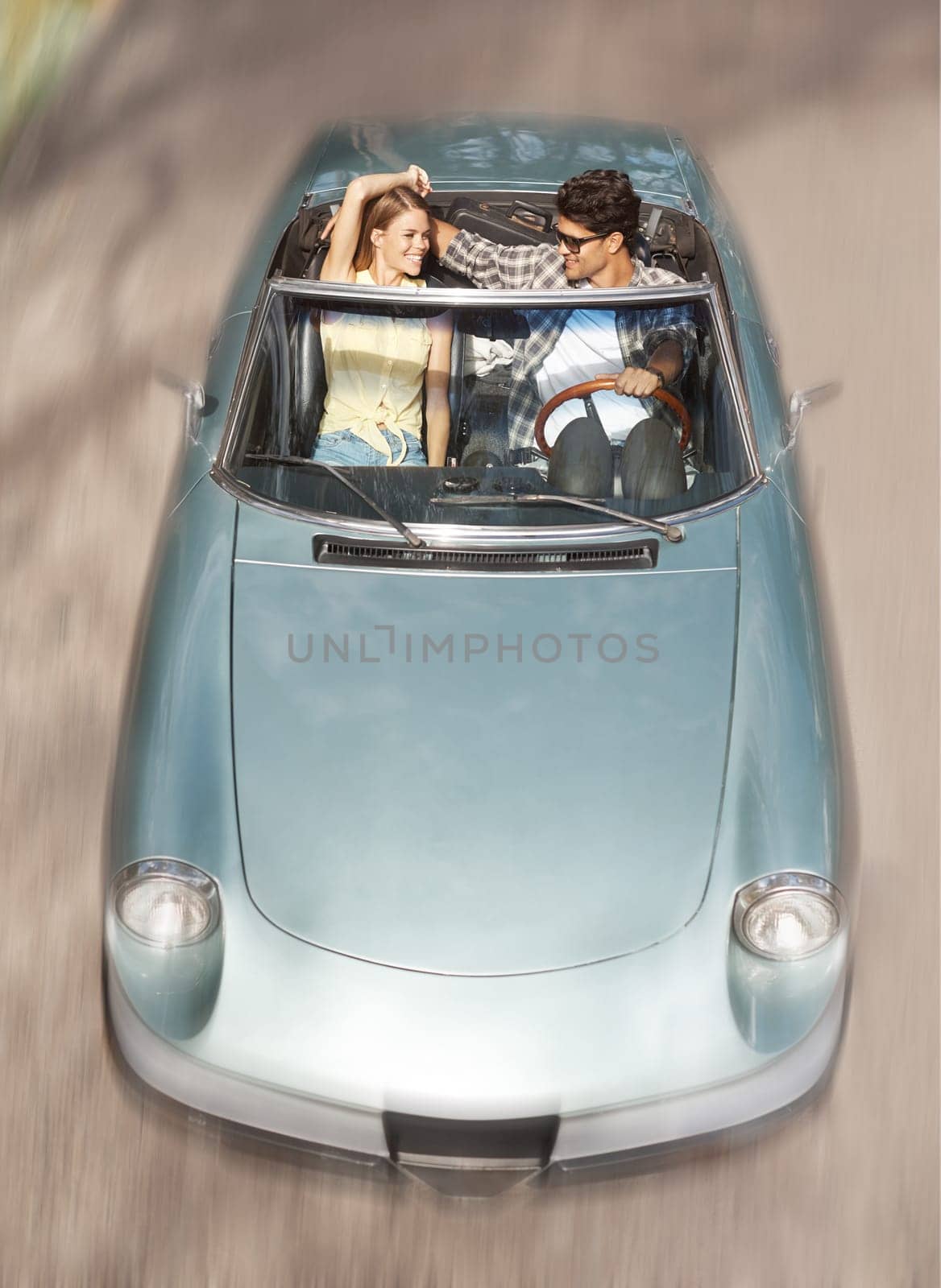 Feeling the wind through my hair. Attractive young couple riding together in an open top sports car. by YuriArcurs